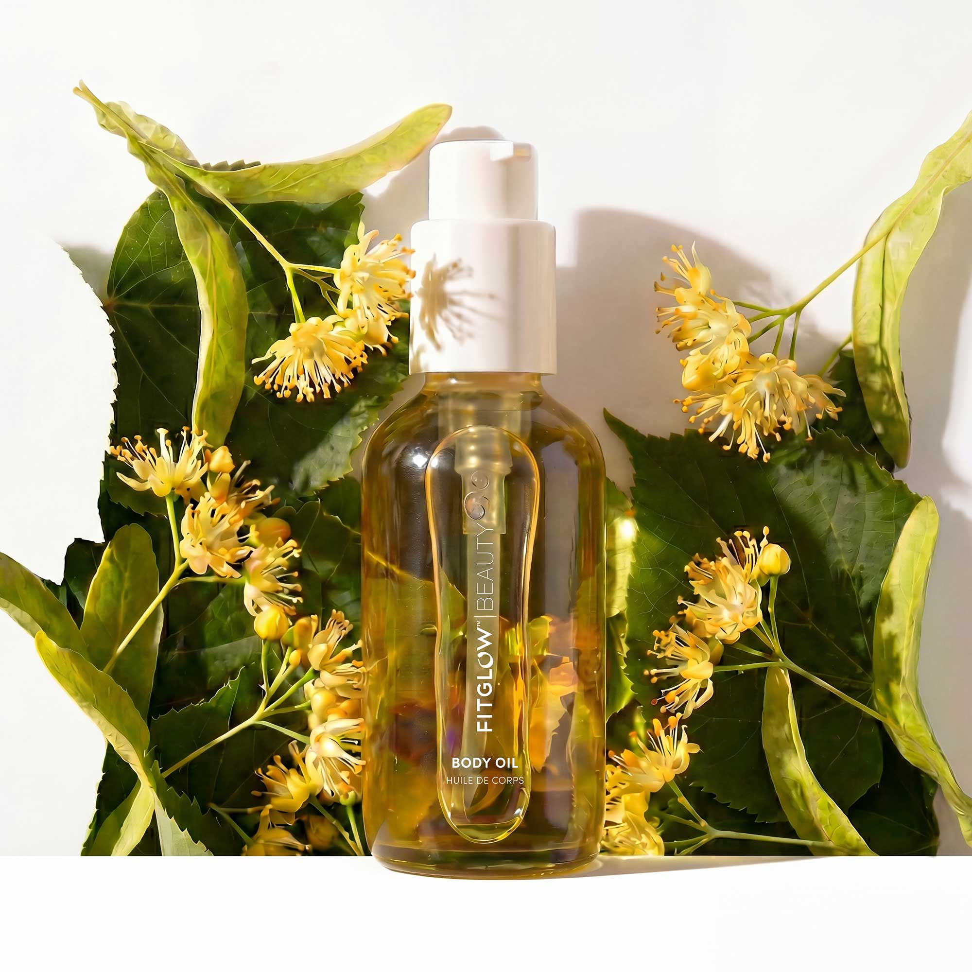 Body oil bottle with flowers and leaves on a white background