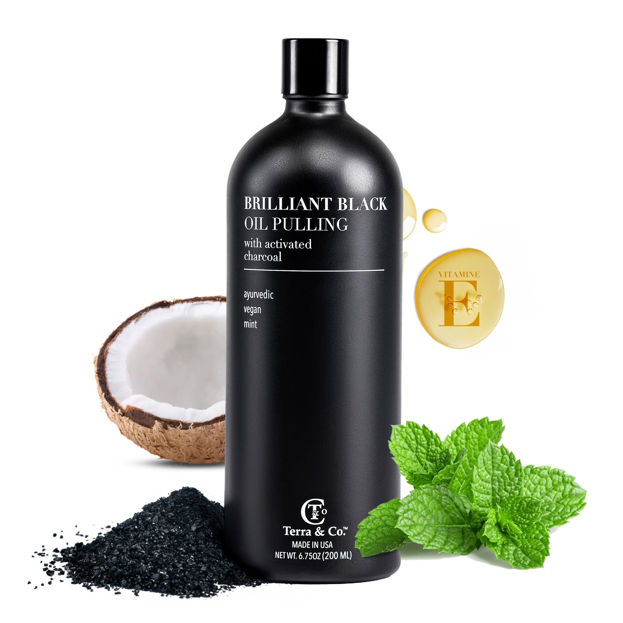 Black bottle of Brilliant Black Oil Pulling with coconut, charcoal, and mint leaves on a white background