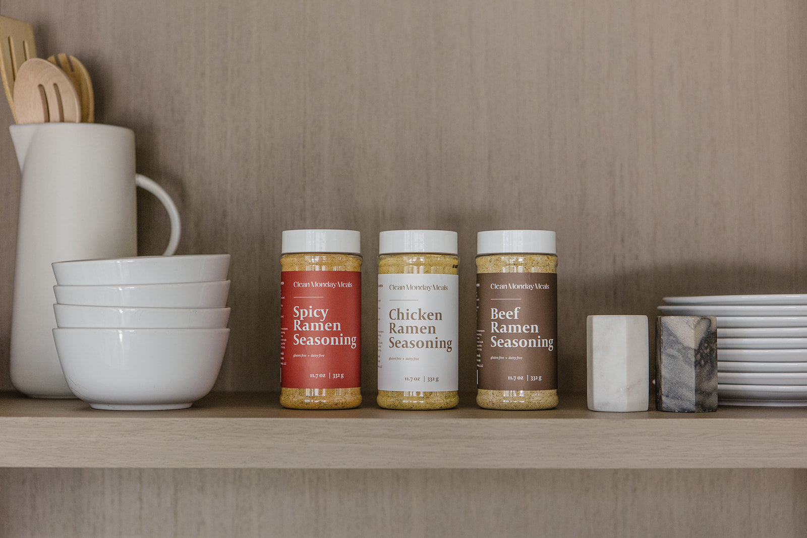 Three jars of ramen seasoning on a kitchen shelf with kitchenware in the background.