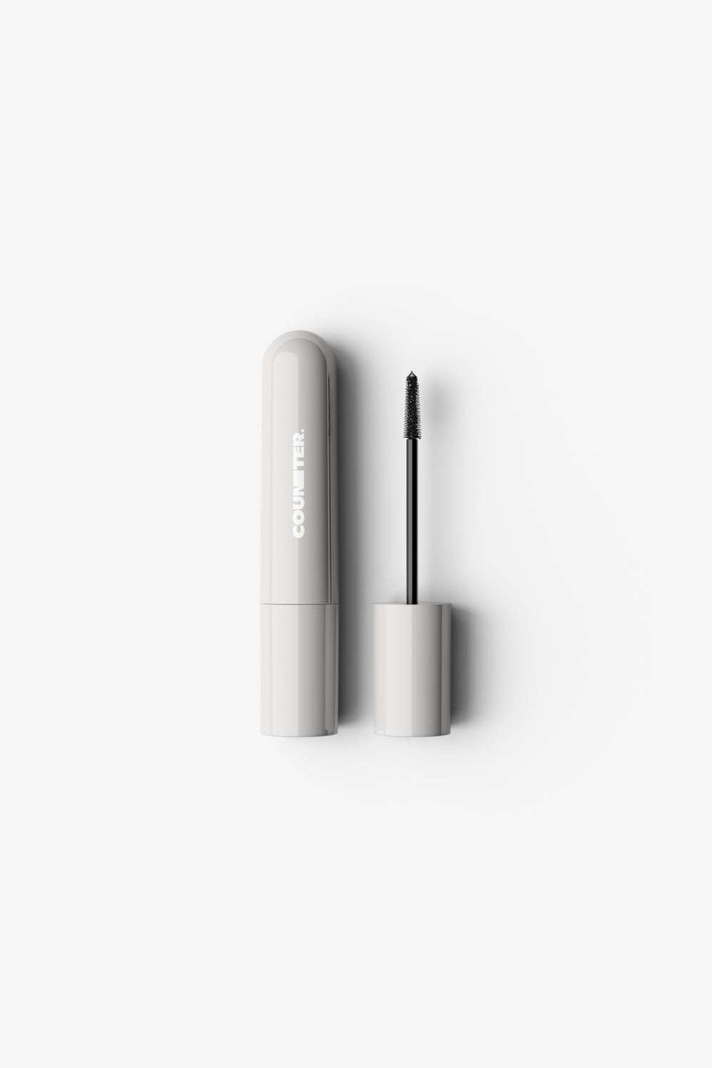 Mascara with white casing and black wand on a light gray background