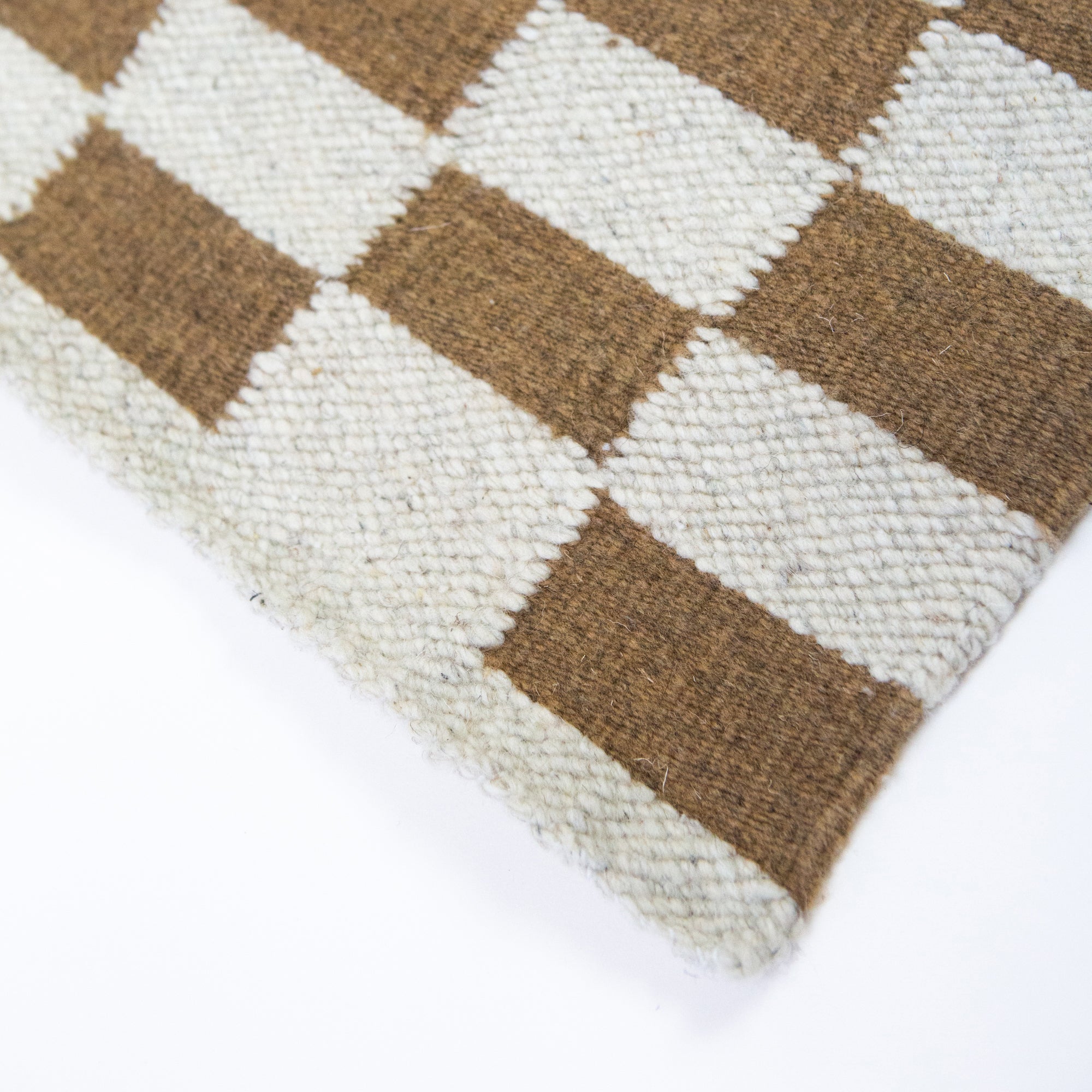 Close-up of a checkered patterned rug with brown and beige squares on a white background