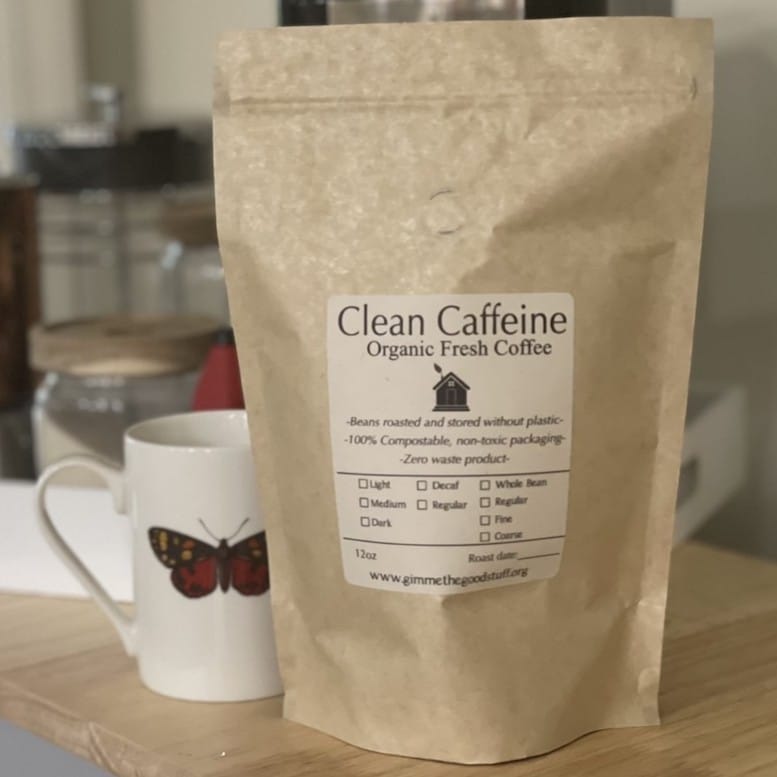 A tan bag of organic coffee sitting next to a white mug with a butterfly on it.