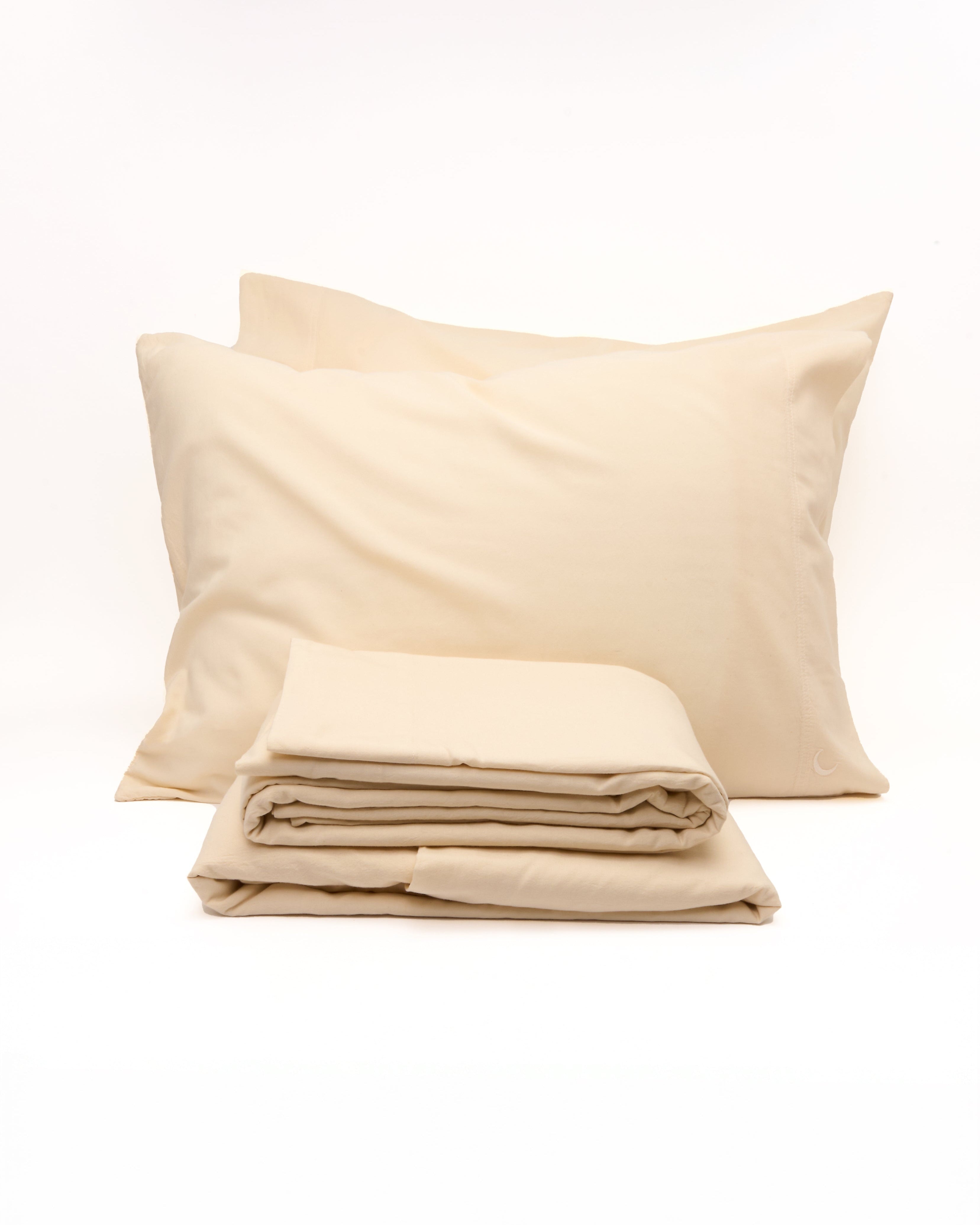 Beige bed sheets and pillowcases on a white background