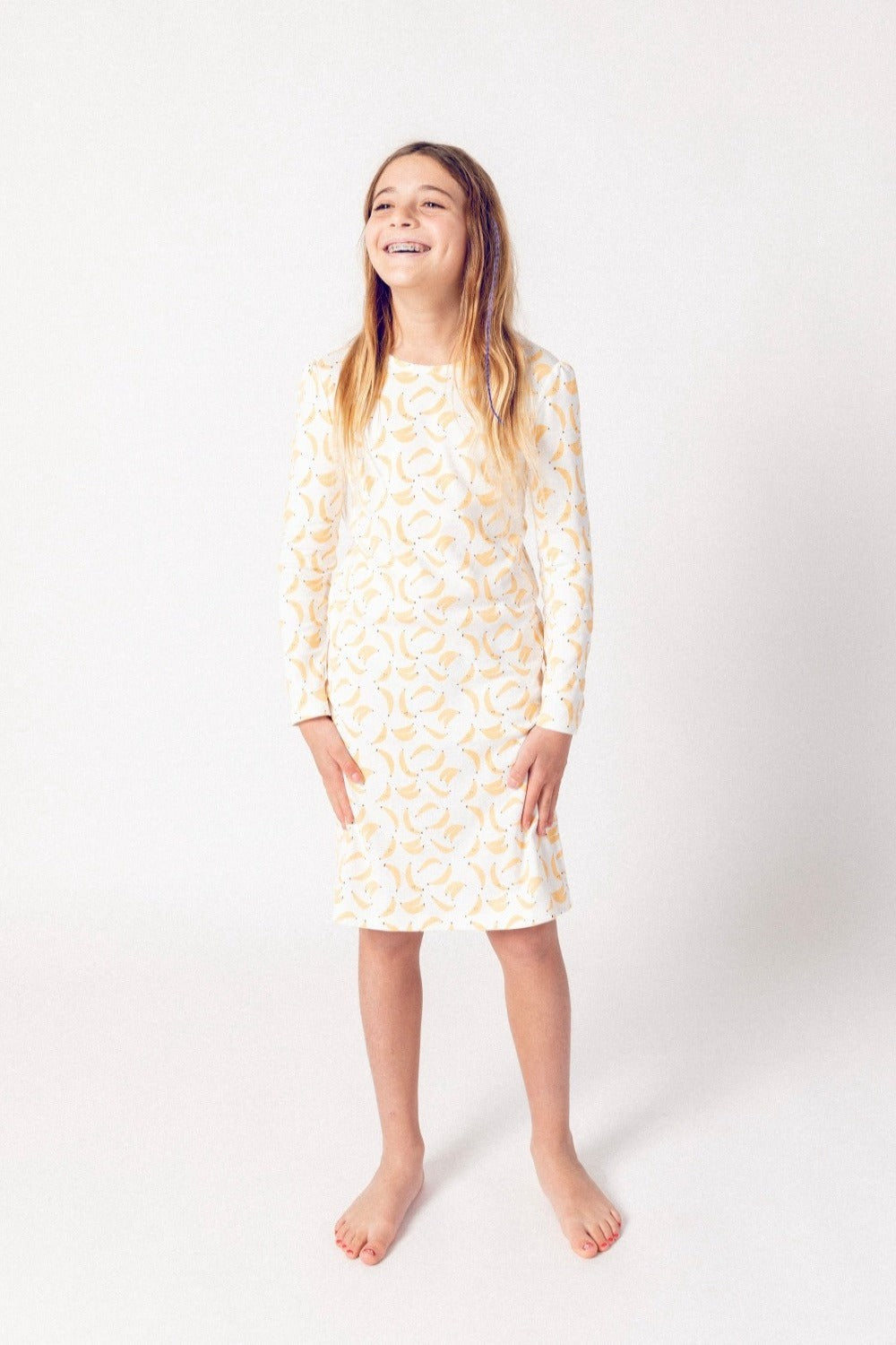 Young girl wearing a long-sleeve nightgown with a pattern on a white background