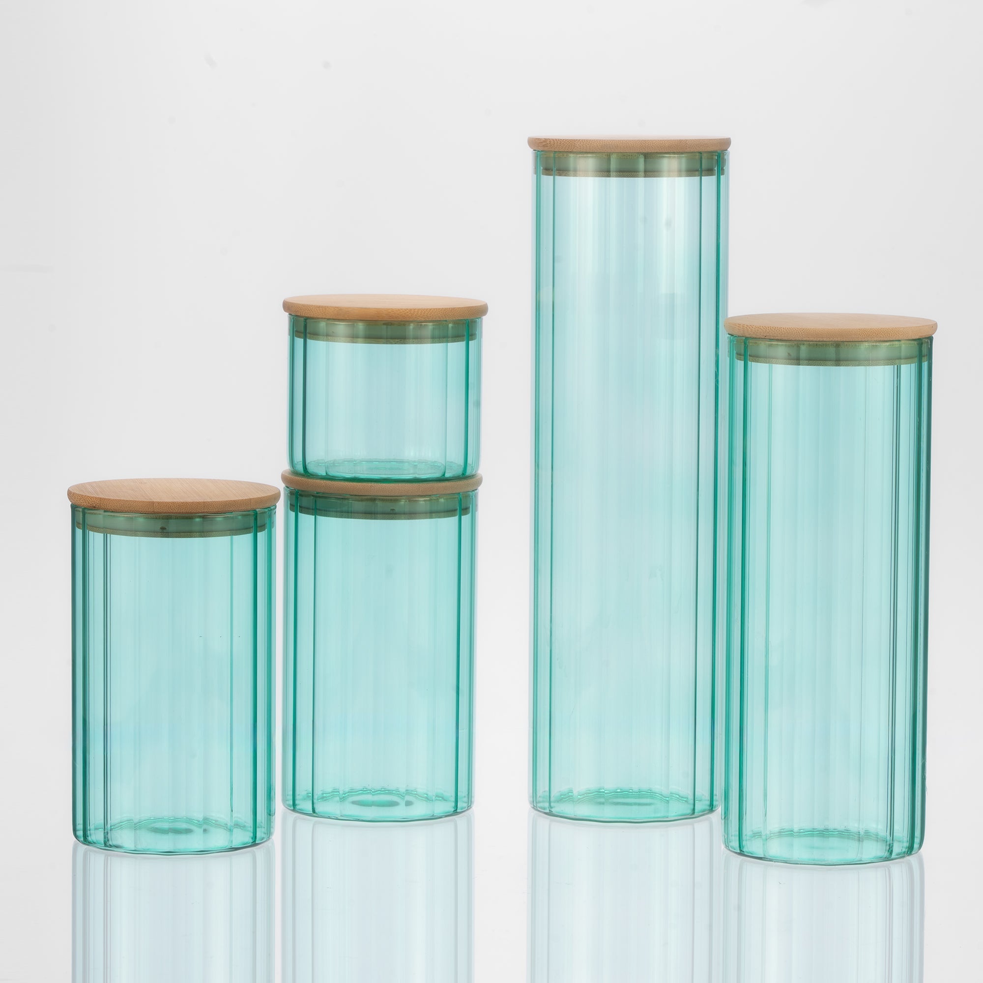 Set of four turquoise glass jars with wooden lids on a white background