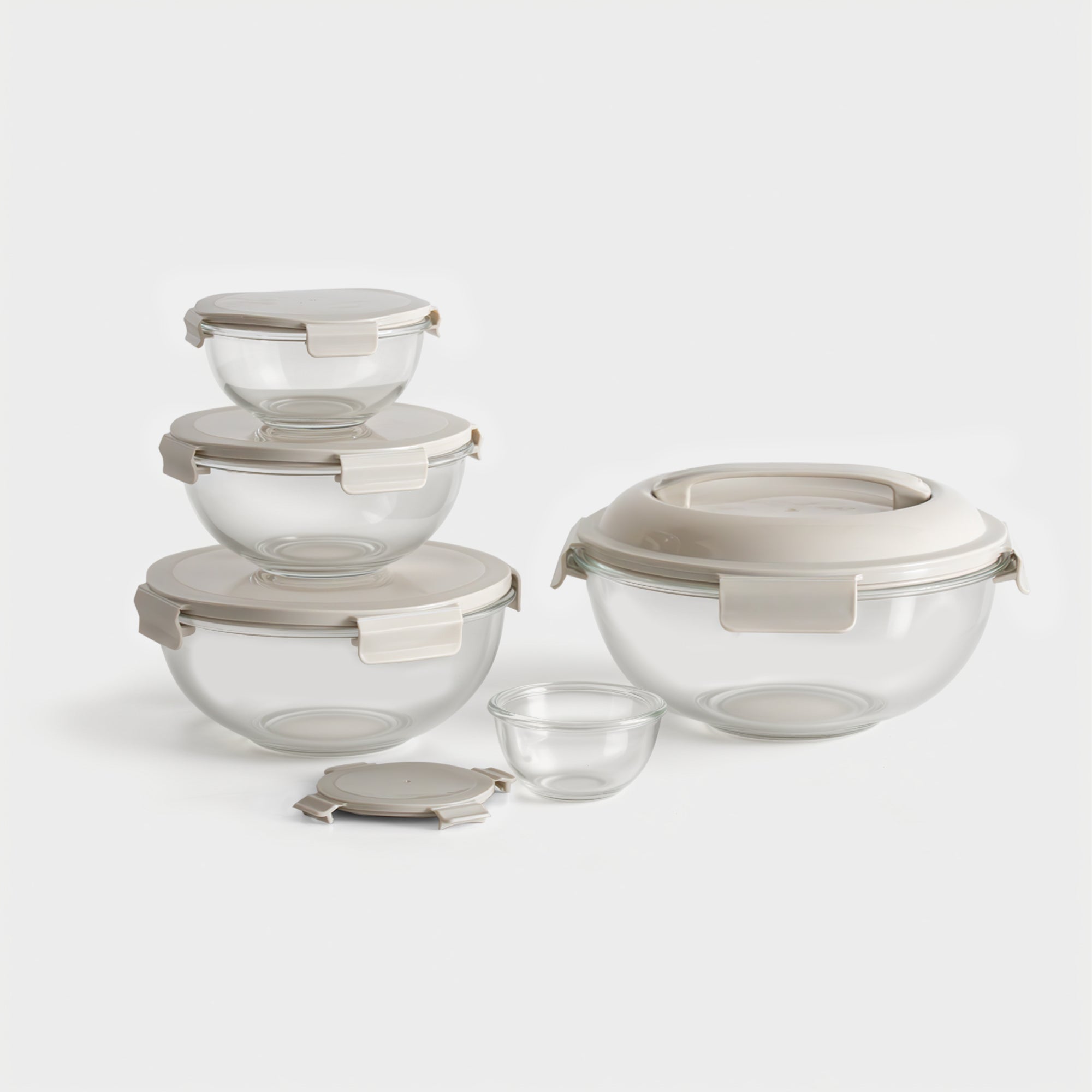 Set of glass food storage containers with beige lids on a white background