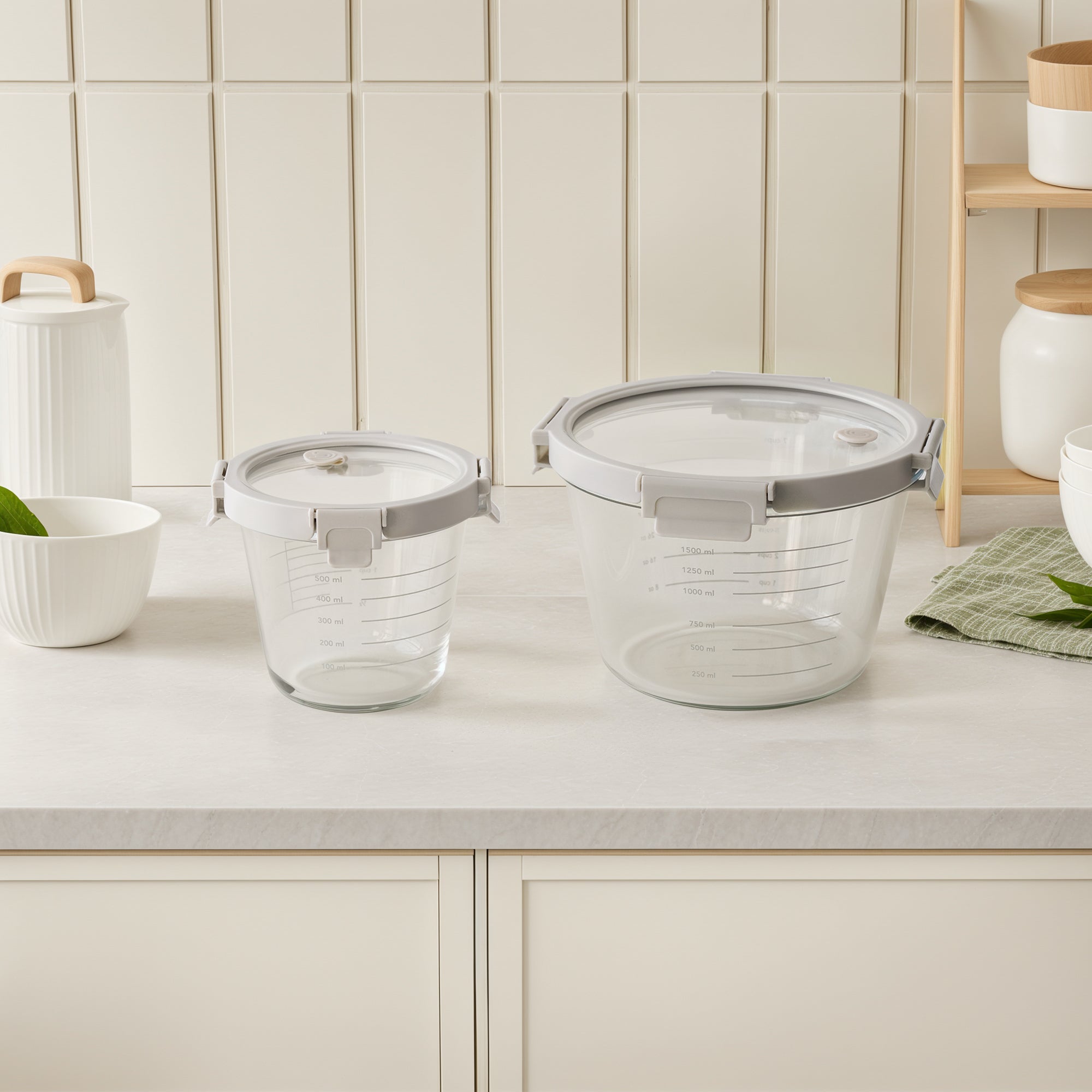 Two glass containers with gray lids on a kitchen counter.