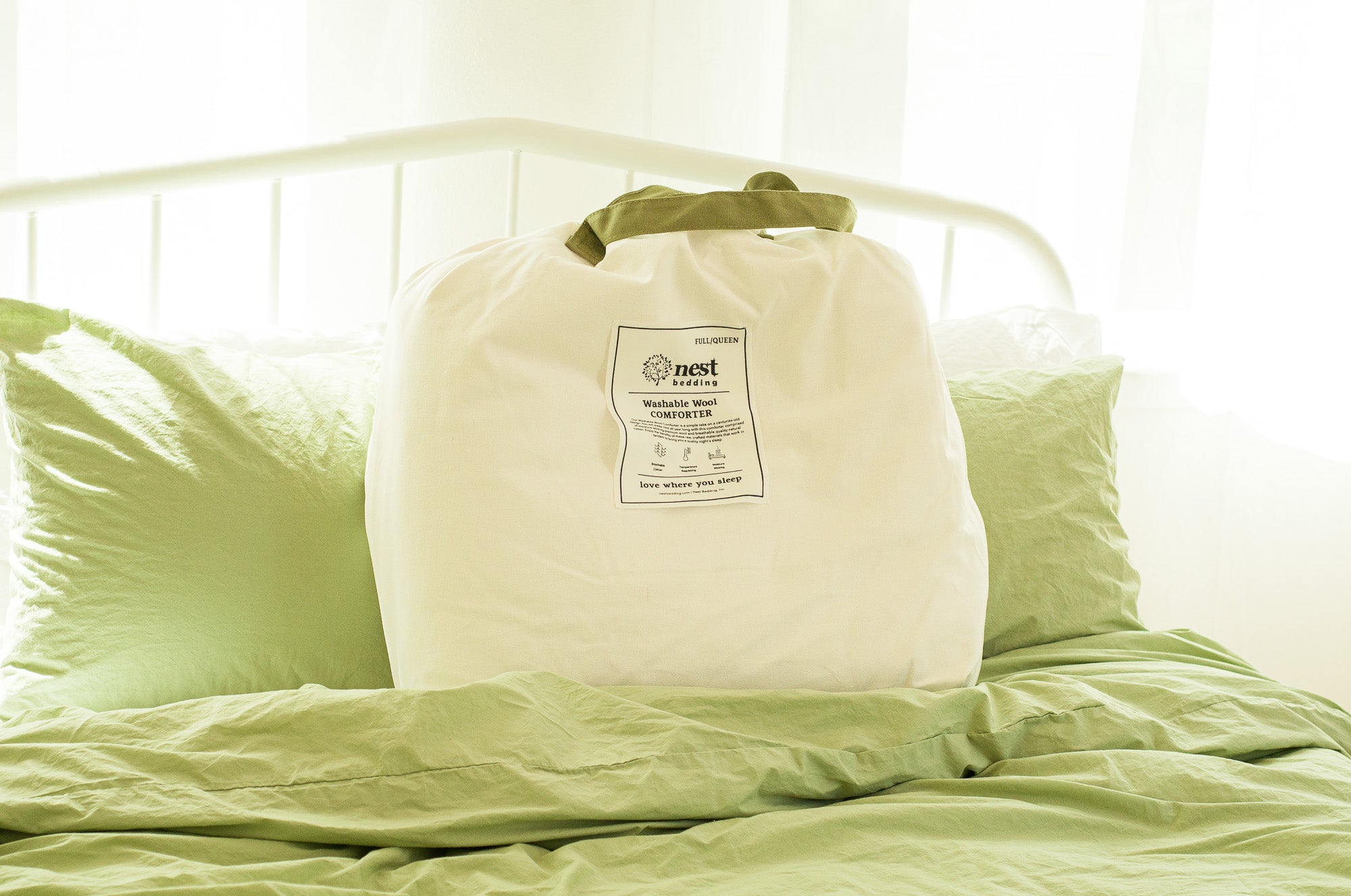 White compression bag with a label on a bed with green bedding