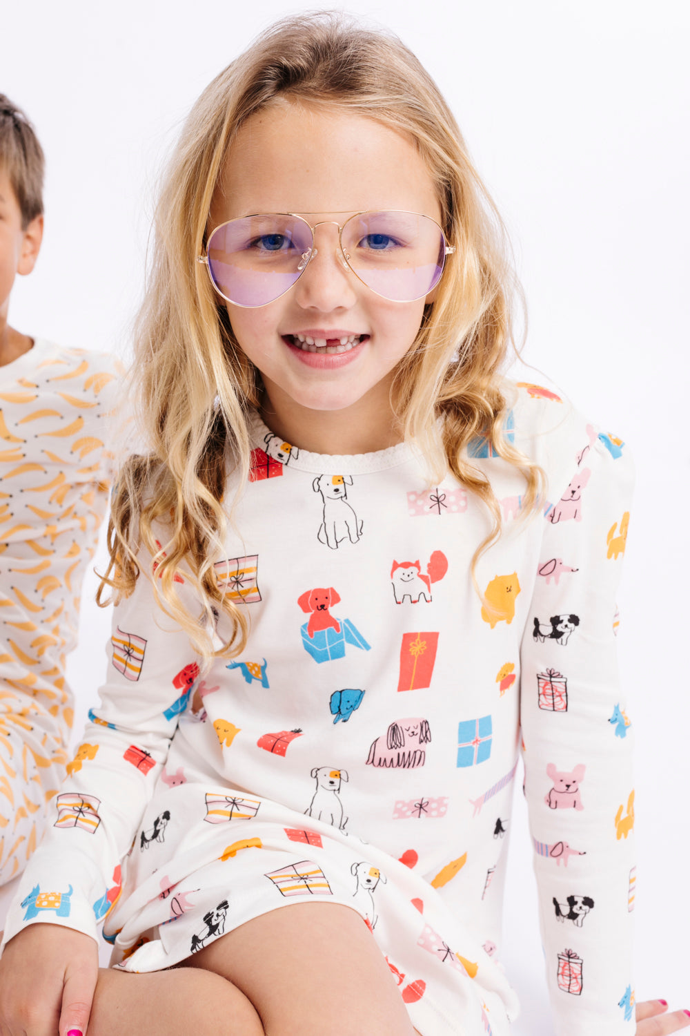 Child wearing a colorful long-sleeve shirt with cartoon designs on a white background
