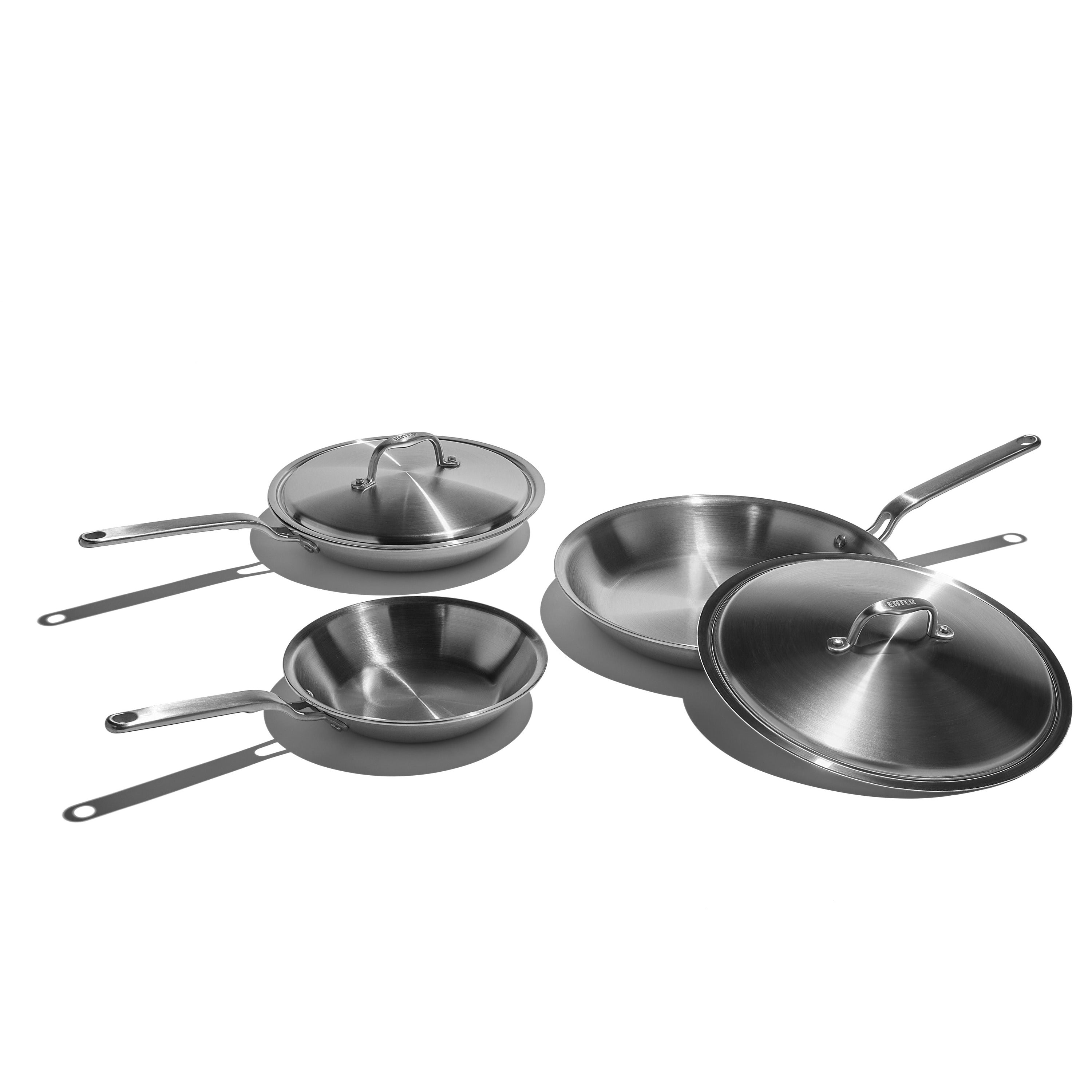 Set of stainless steel cookware including pans and lids on a white background