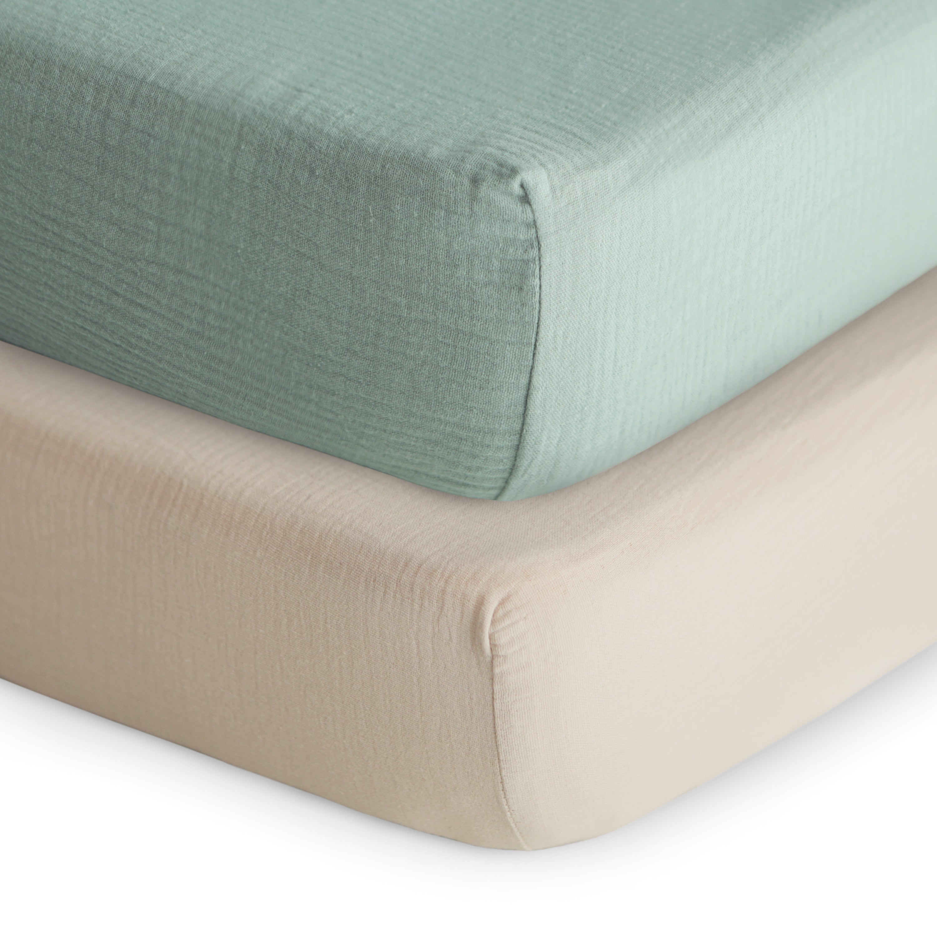 Two fitted sheets, one green and one beige, on a white background
