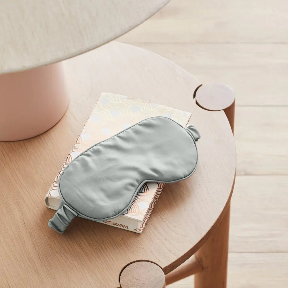 Gray sleep mask on a book on a wooden table