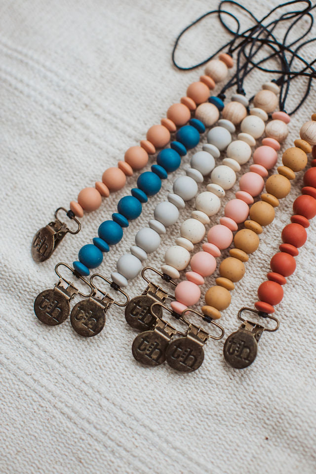 Set of colorful beaded necklaces with metal pendants on a textured white surface