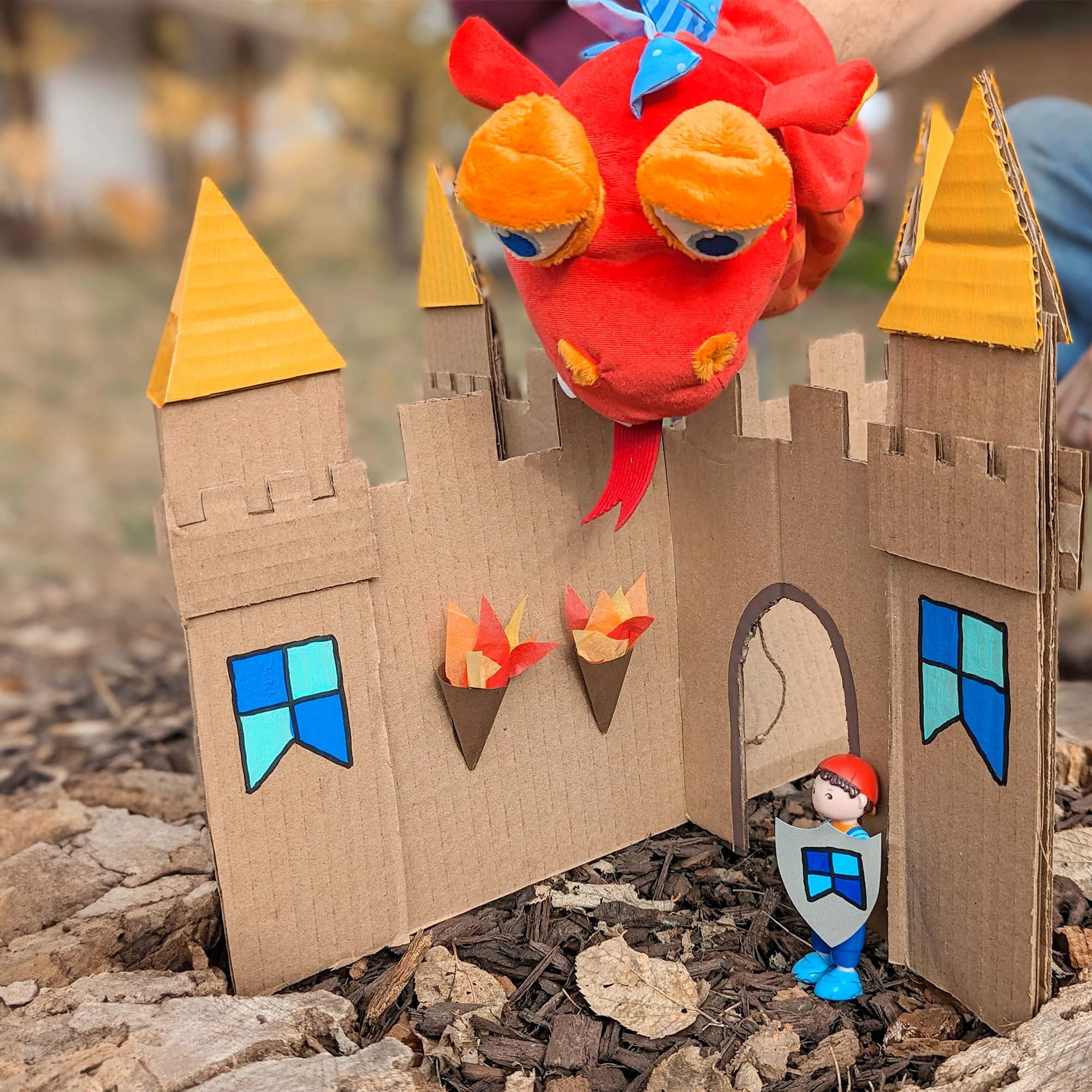 Cardboard castle with dragon and knight toy on a natural background