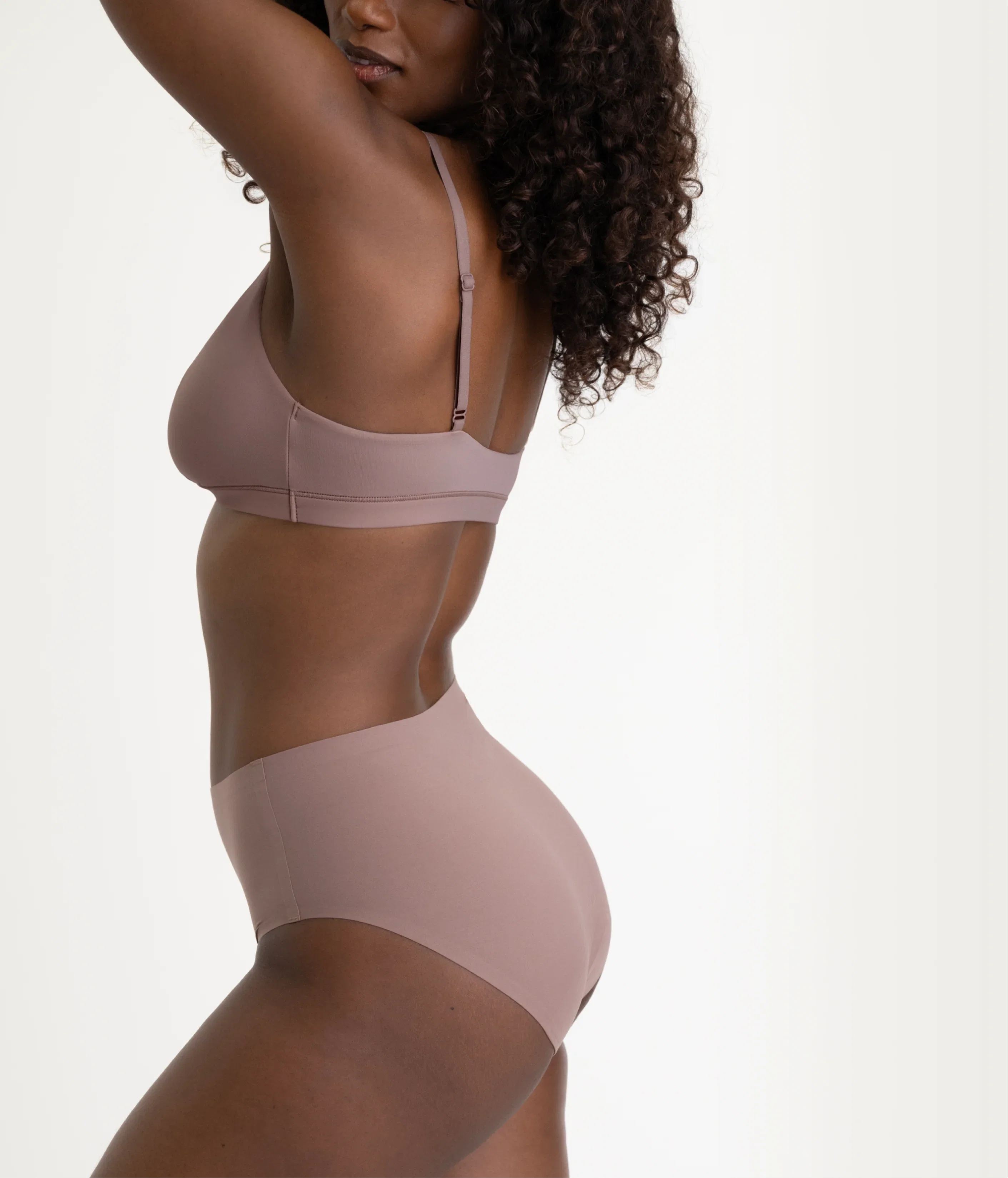 Woman wearing a beige bra and panties set on a plain background