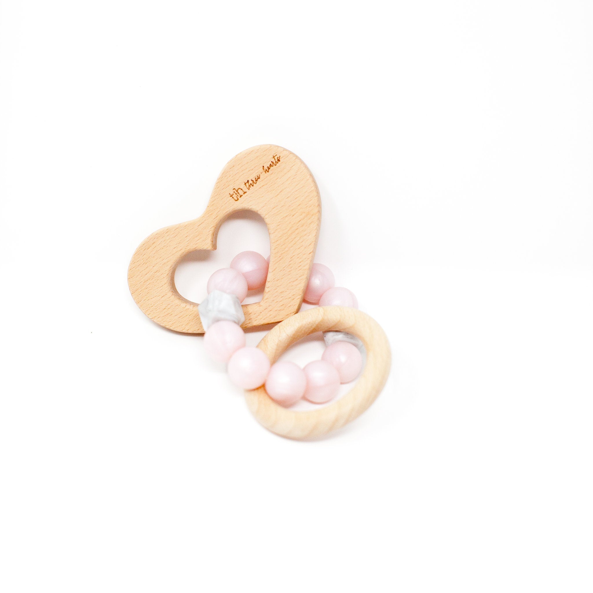 Wooden heart-shaped teether with pink and white beads on a white background