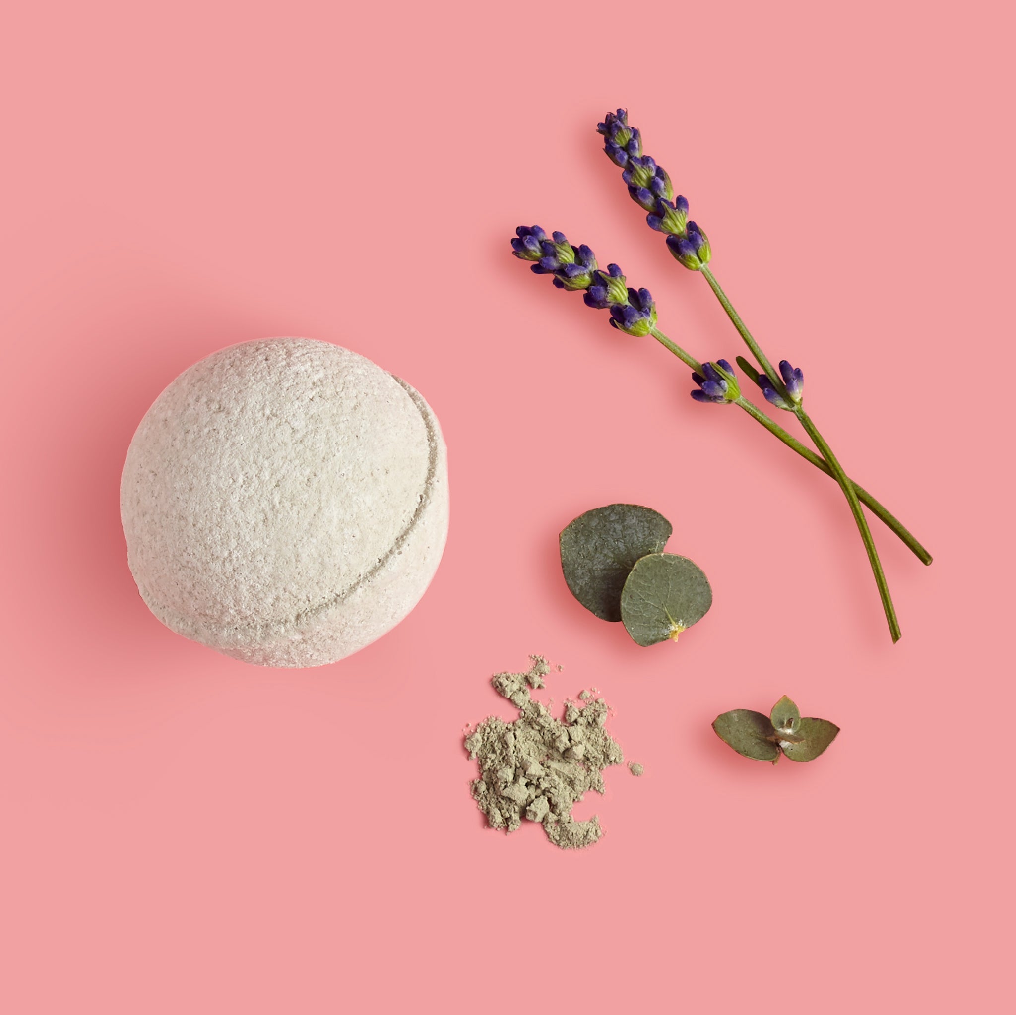 Bath bomb with lavender and eucalyptus leaves on a pink background
