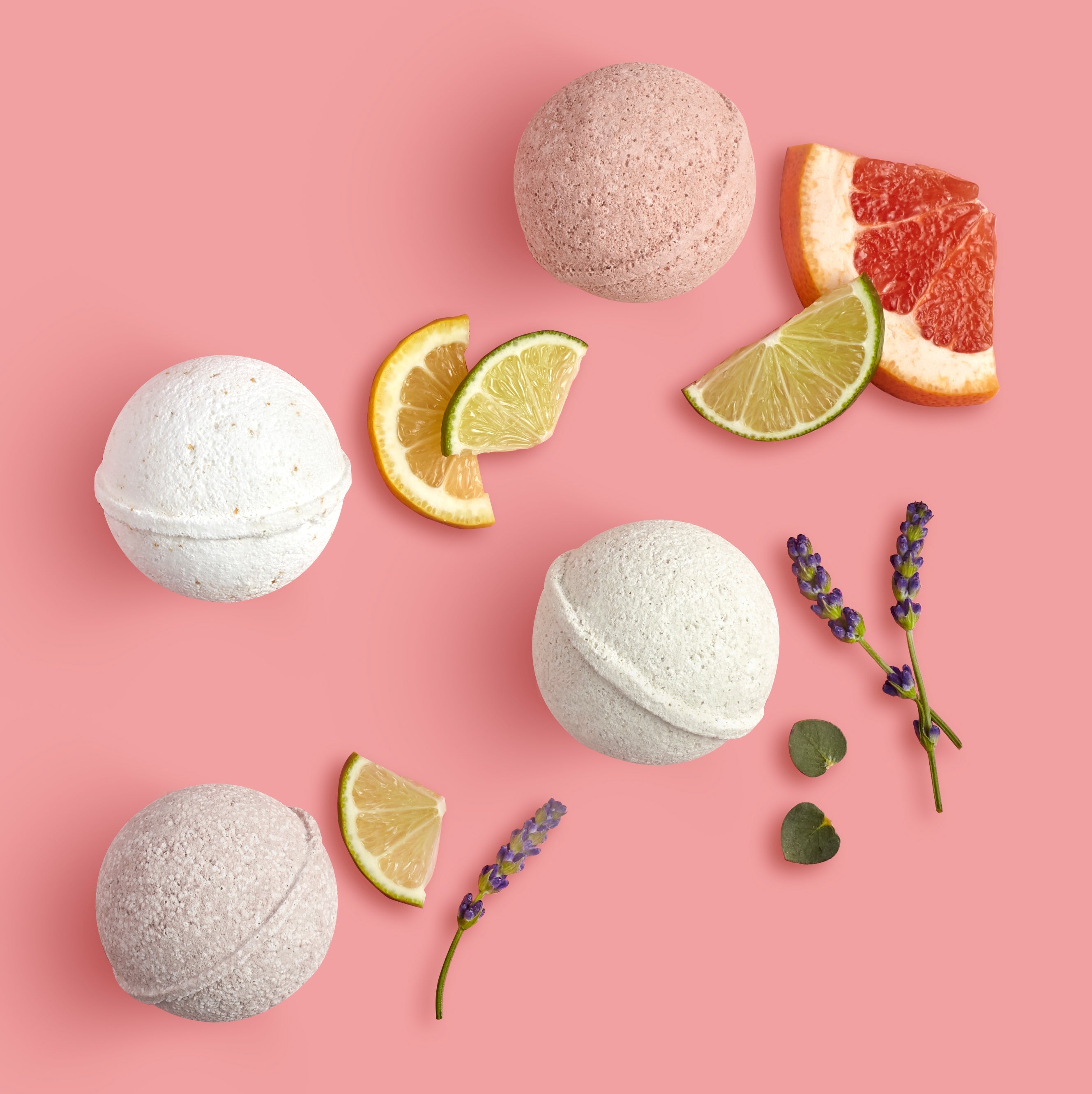 Bath bombs with citrus slices and lavender on a pink background