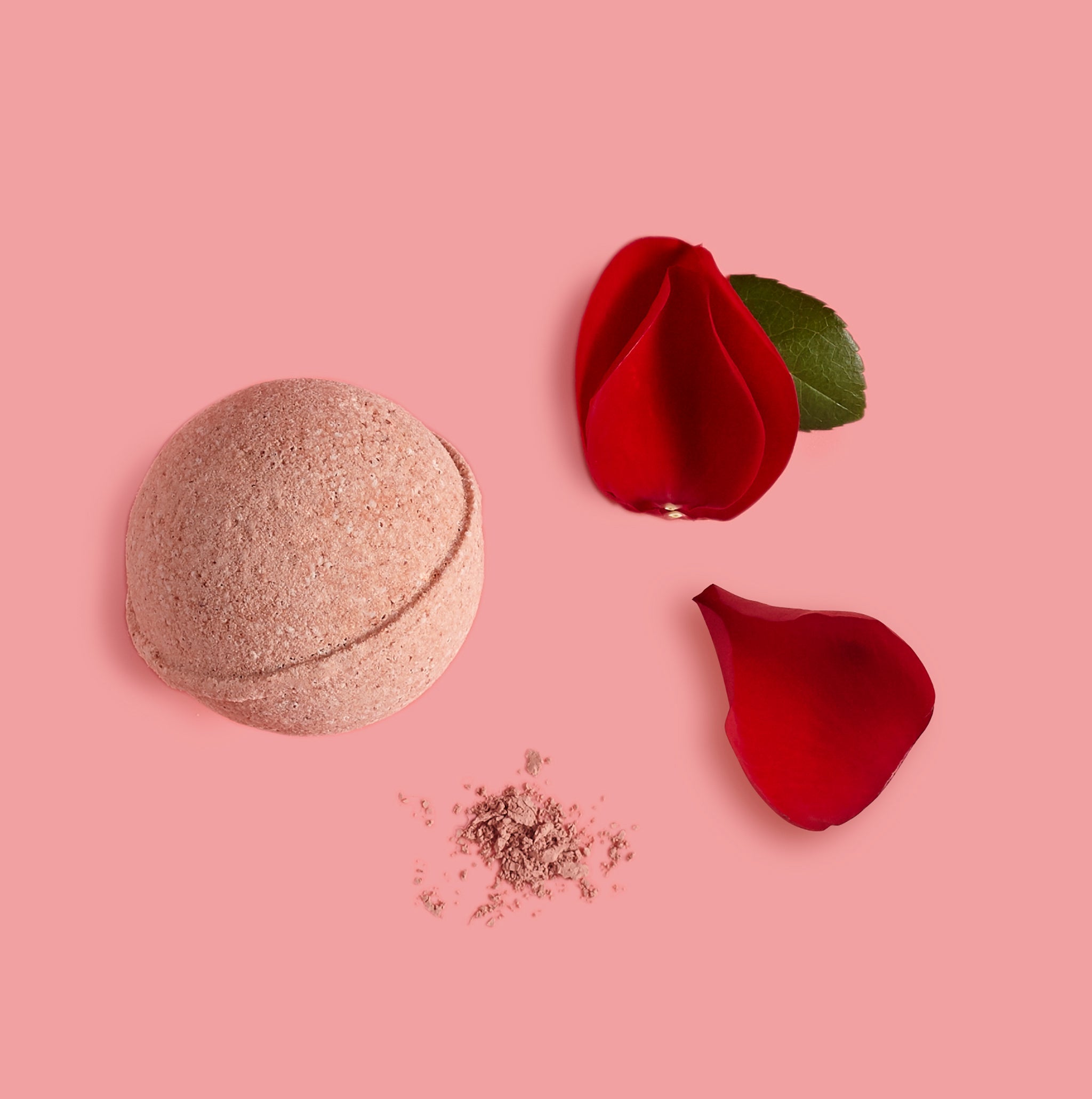 Bath bomb with red flower petals on a pink background