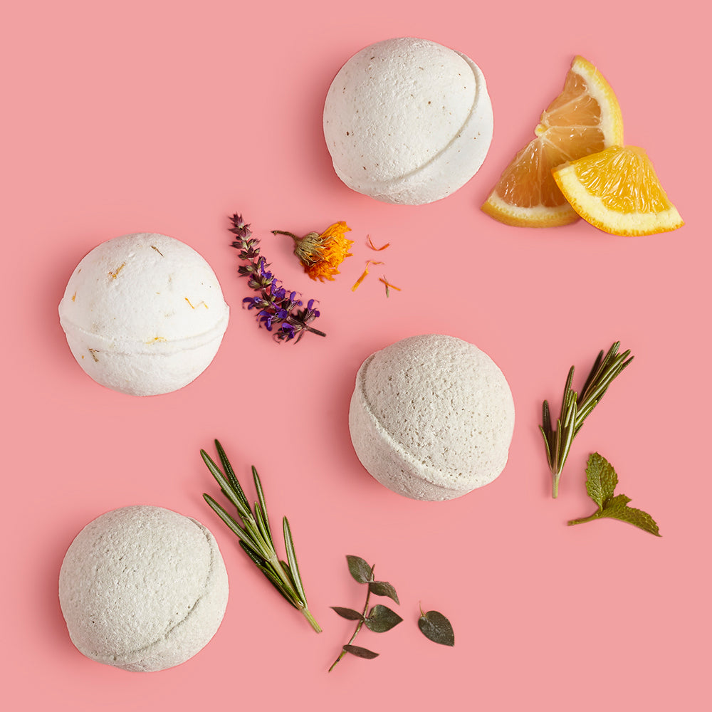 Bath bombs with herbs and lemon slices on a pink background