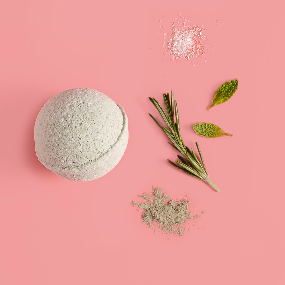 Bath bomb with rosemary leaves and powder on a pink background