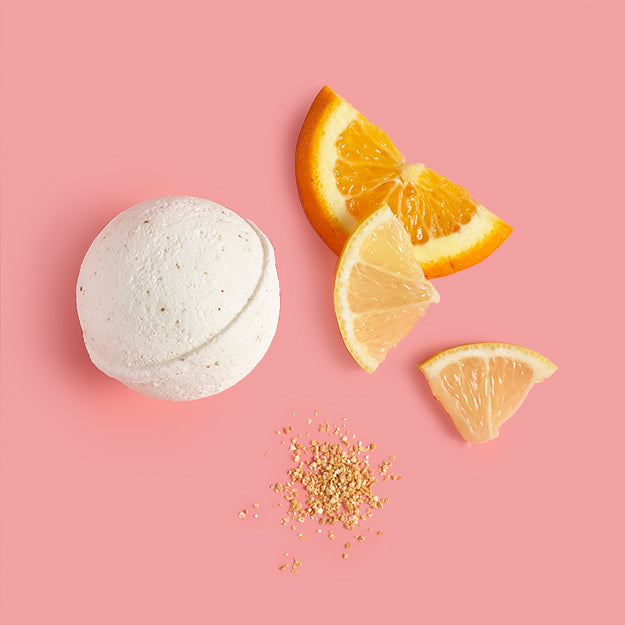 Bath bomb with orange and lemon slices on a pink background
