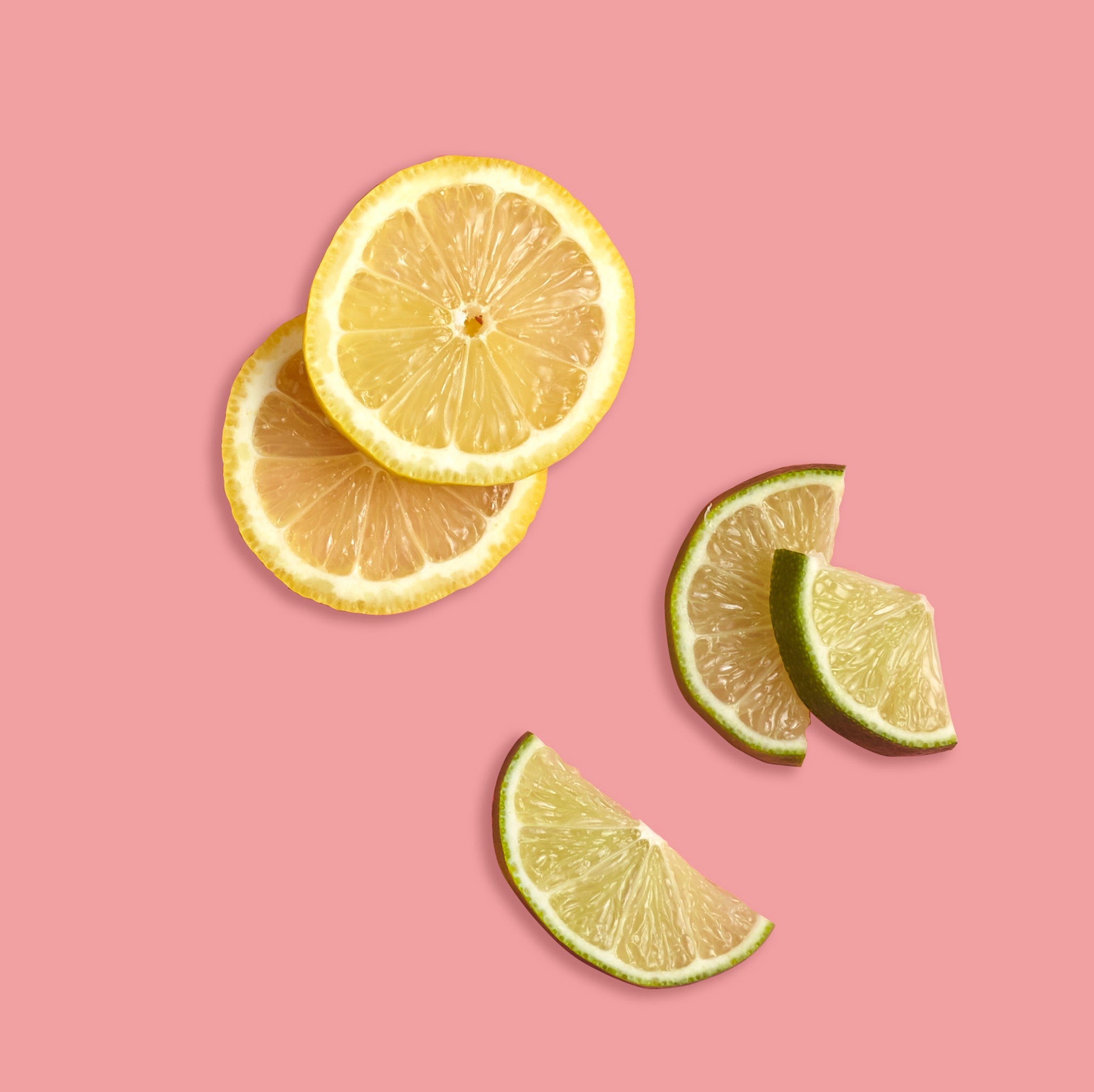 Sliced lemon and lime on a pink background