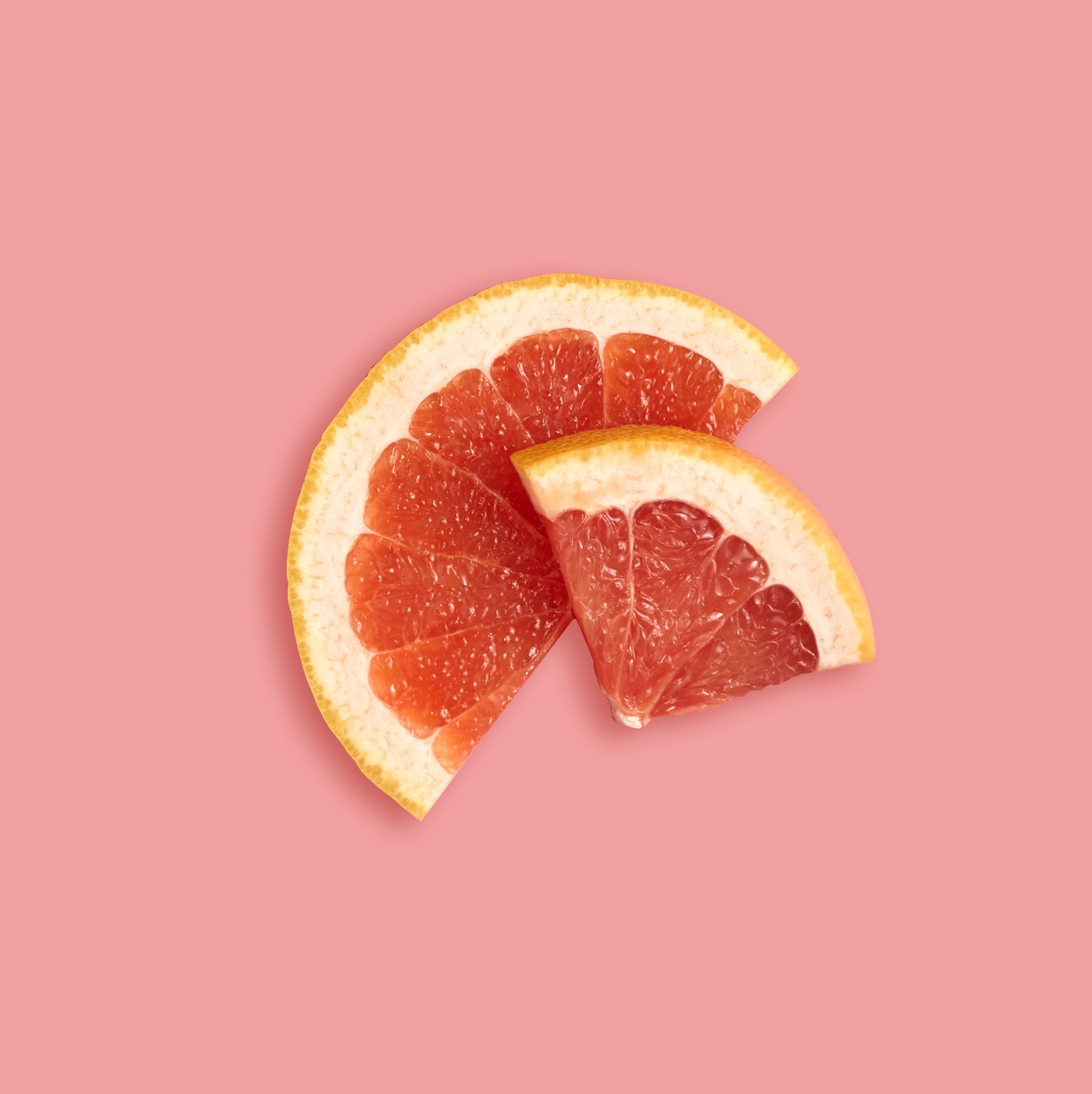 Two grapefruit wedges on a pink background