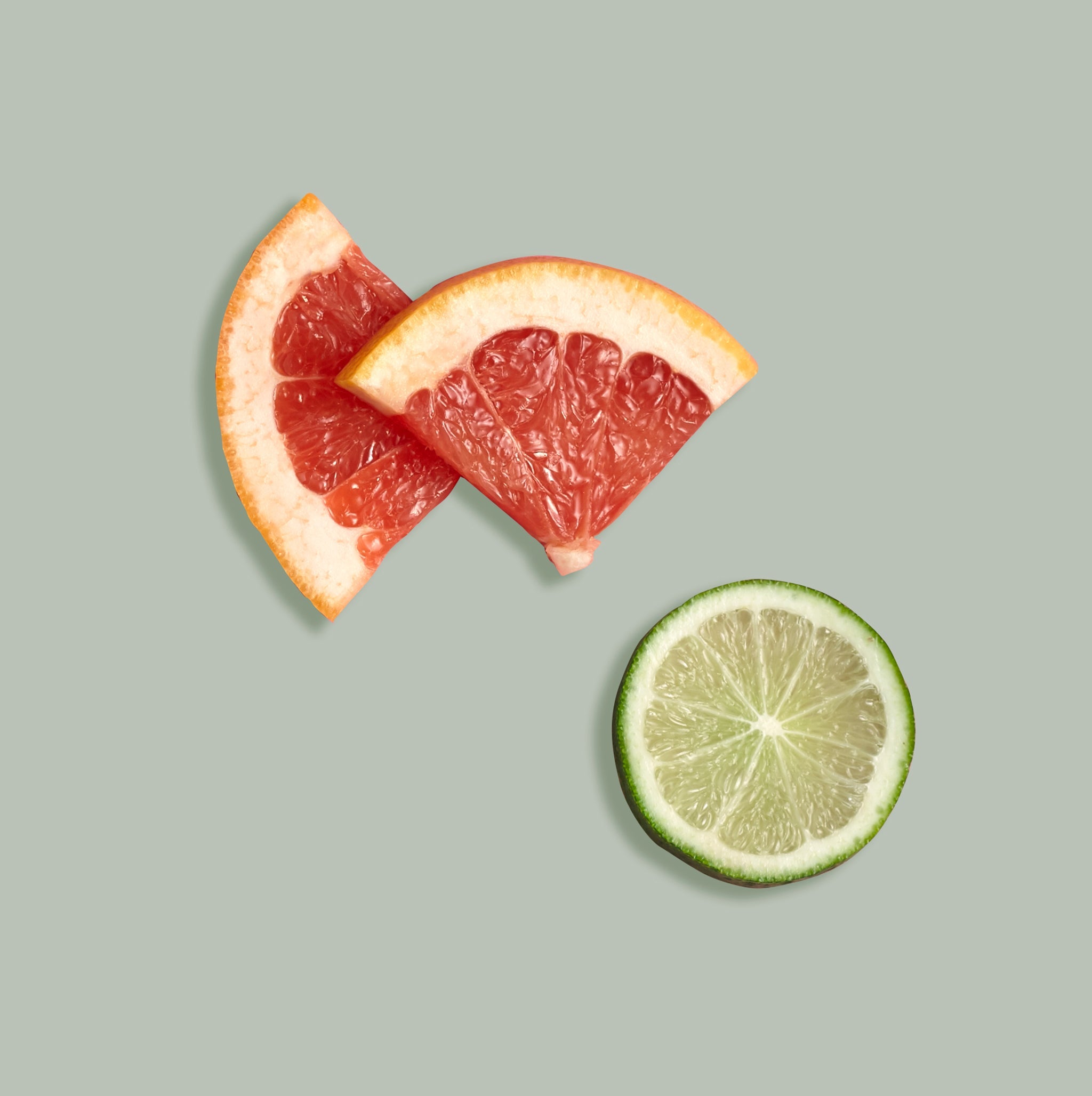 Sliced grapefruit and lime on a light green background