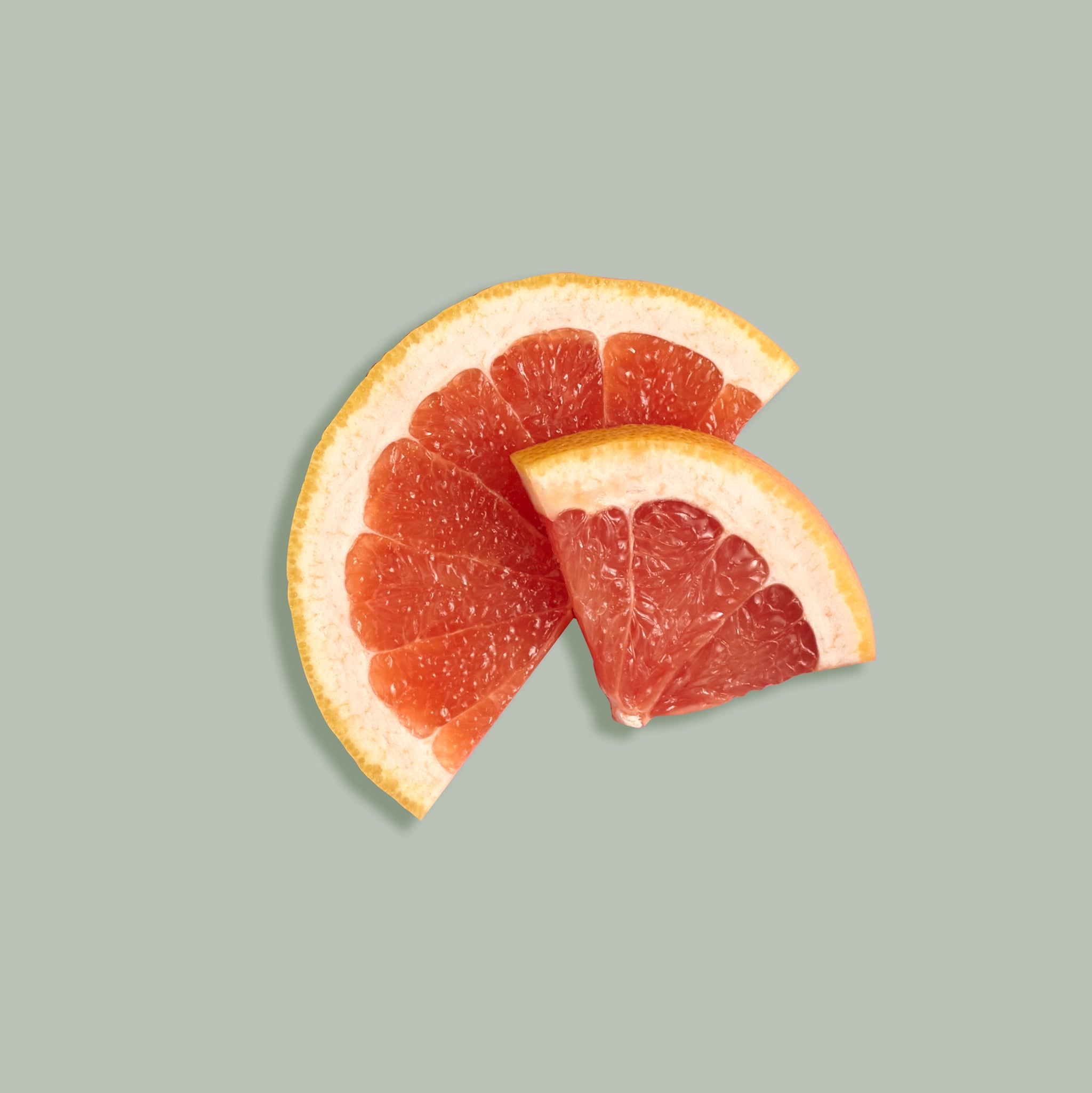 Two wedges of grapefruit on a light green background