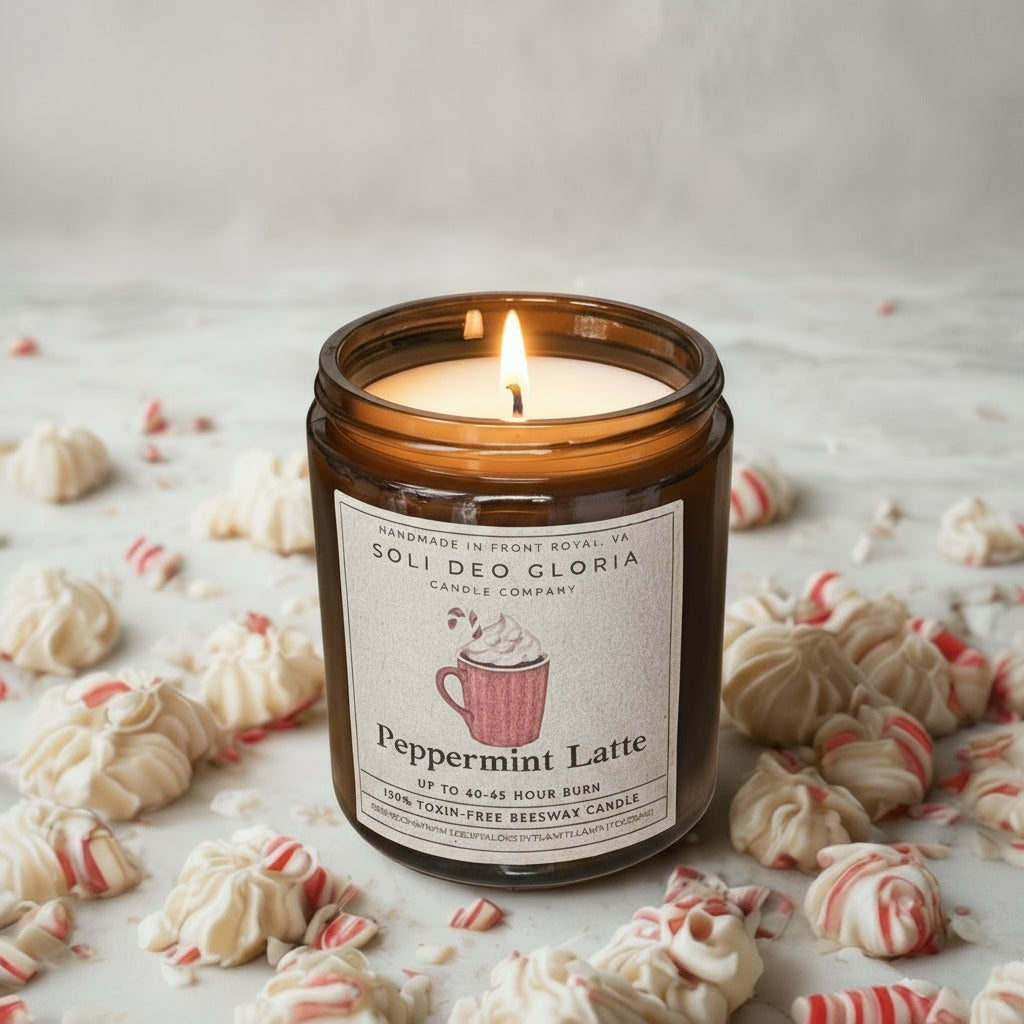 Scented candle labeled 'Peppermint Latte' by Solideo Gloria on a surface with cookies and candy canes.