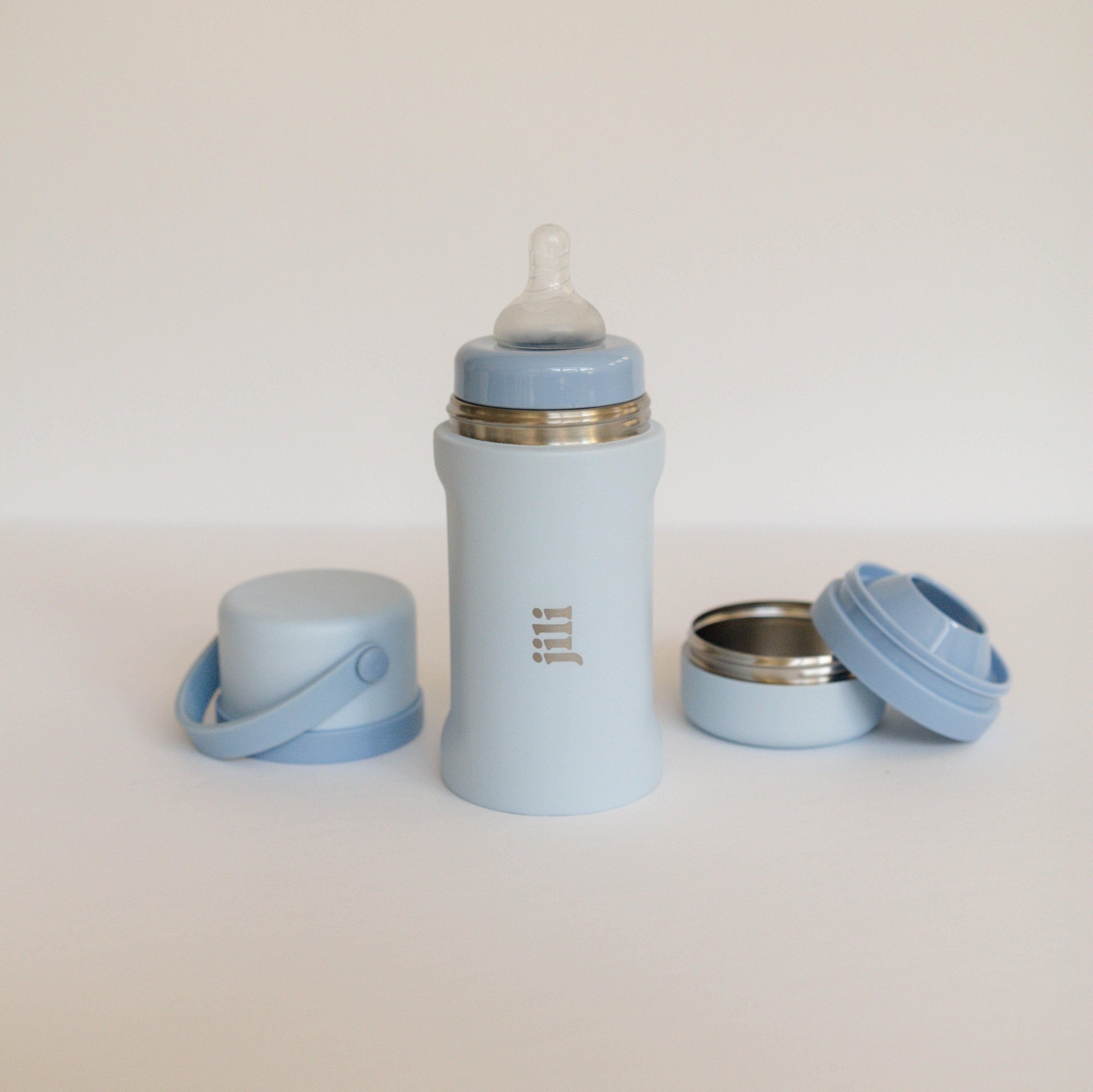Light blue baby bottle with accessories on a white background