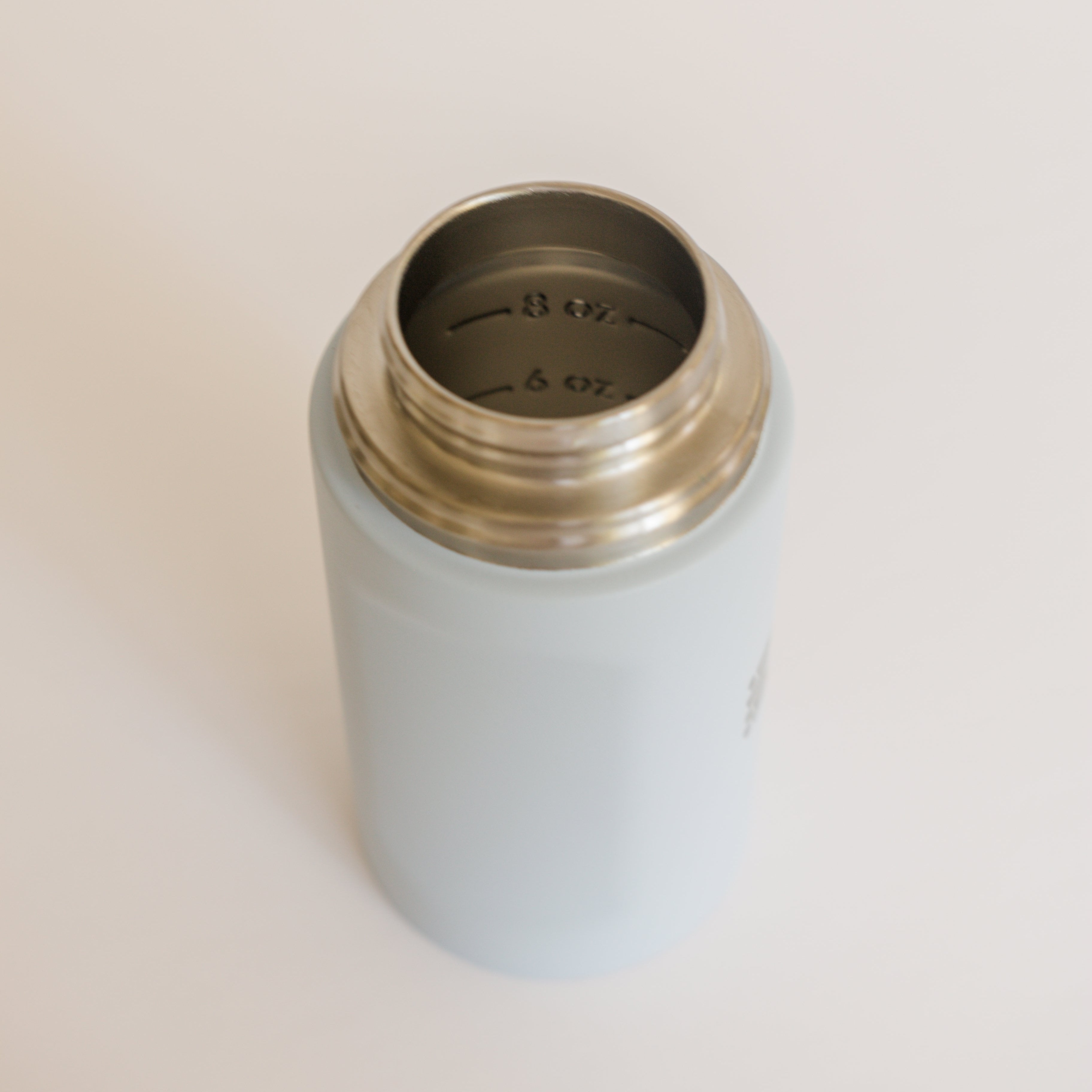 Light blue thermos with gold lid on a beige background