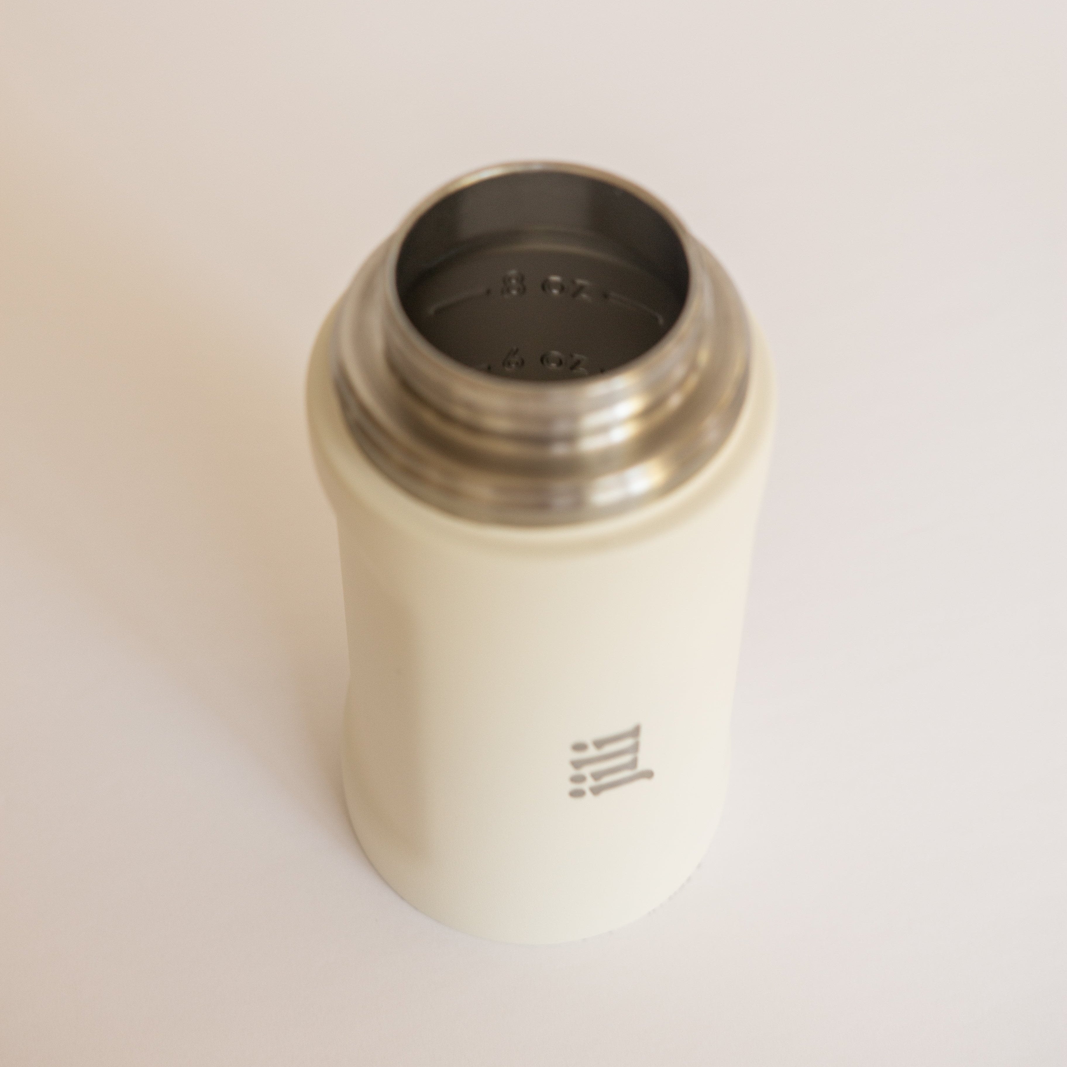 Metallic shaker with a dark interior on a light beige background