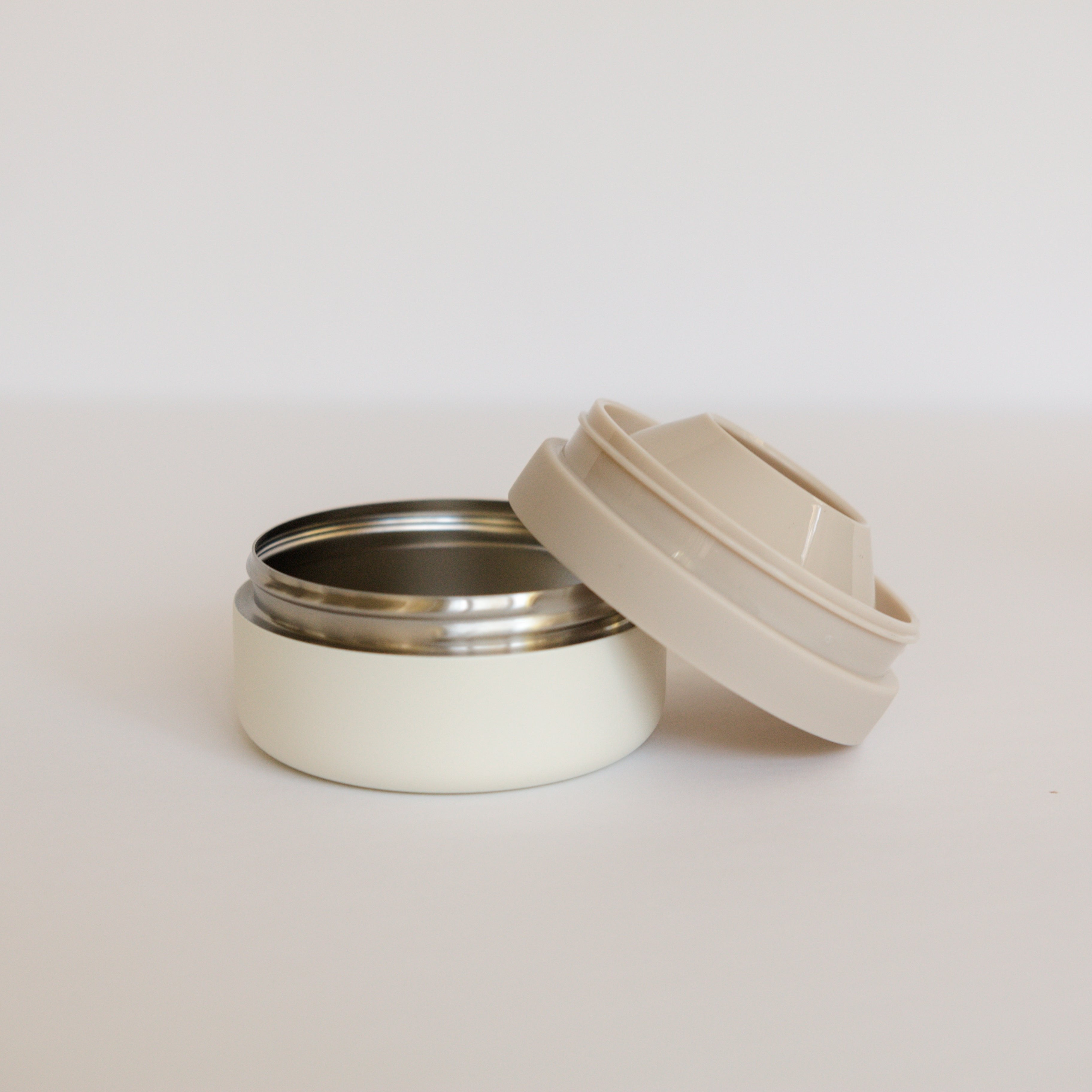 White thermos with beige lid on a light gray background