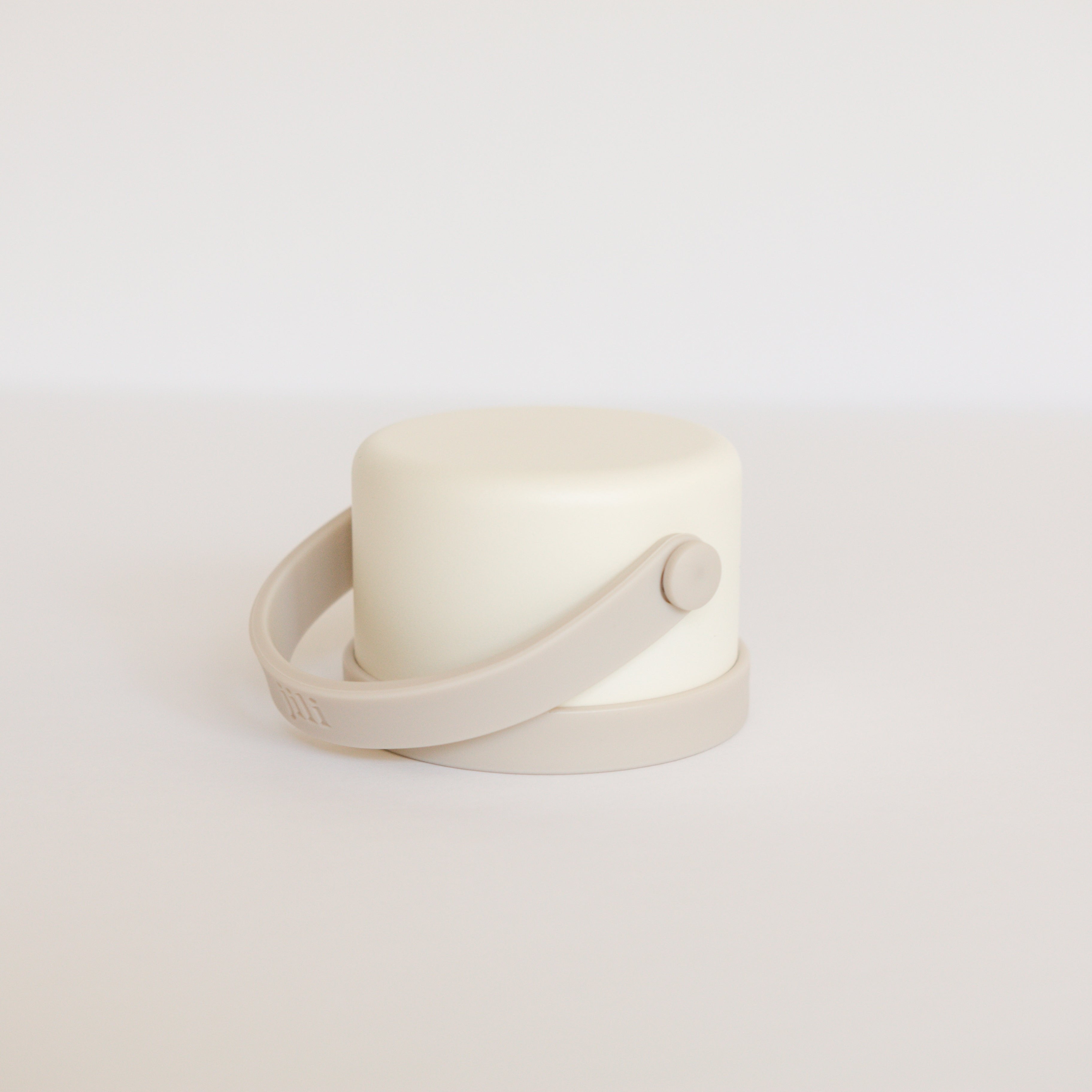 White cylindrical container with a strap on a light gray background
