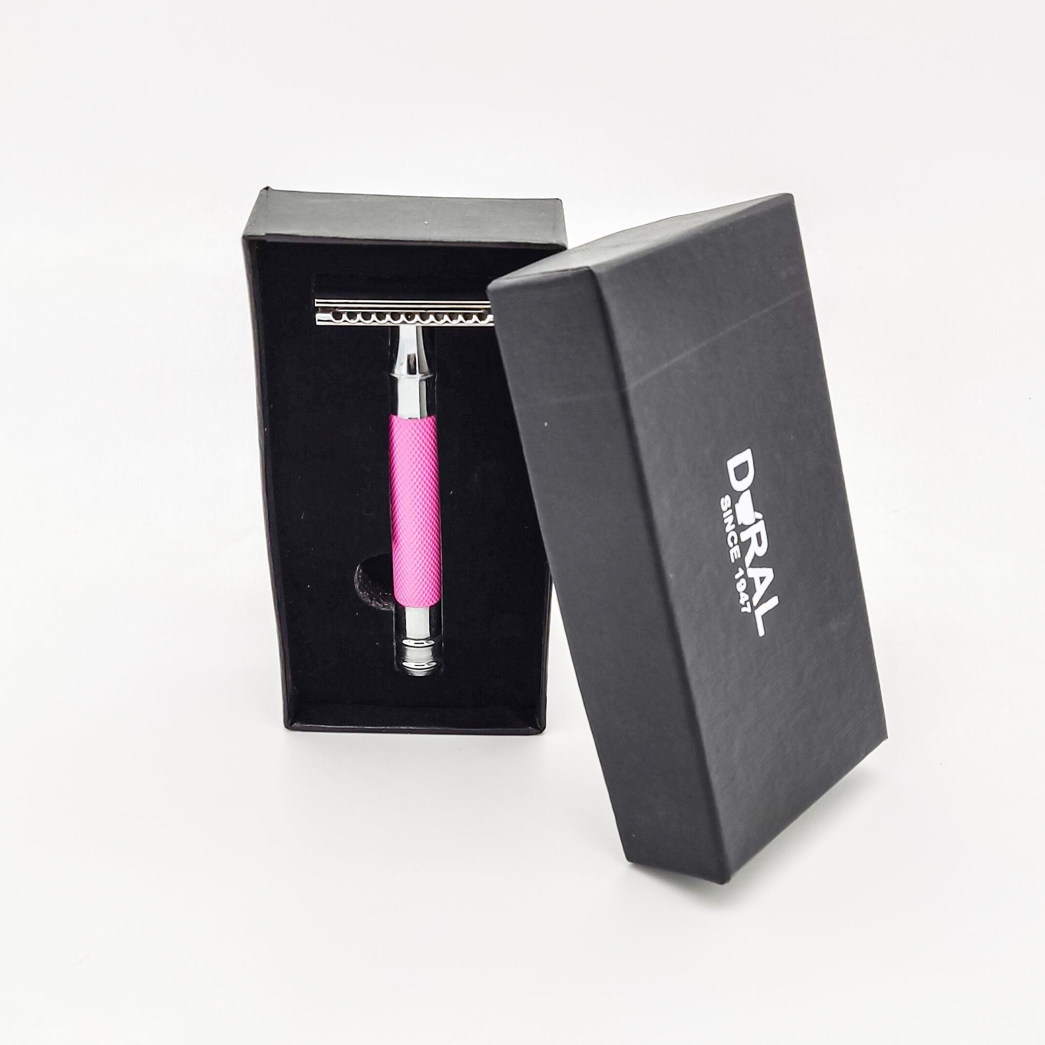 Pink safety razor in an open black Doral box on a white background