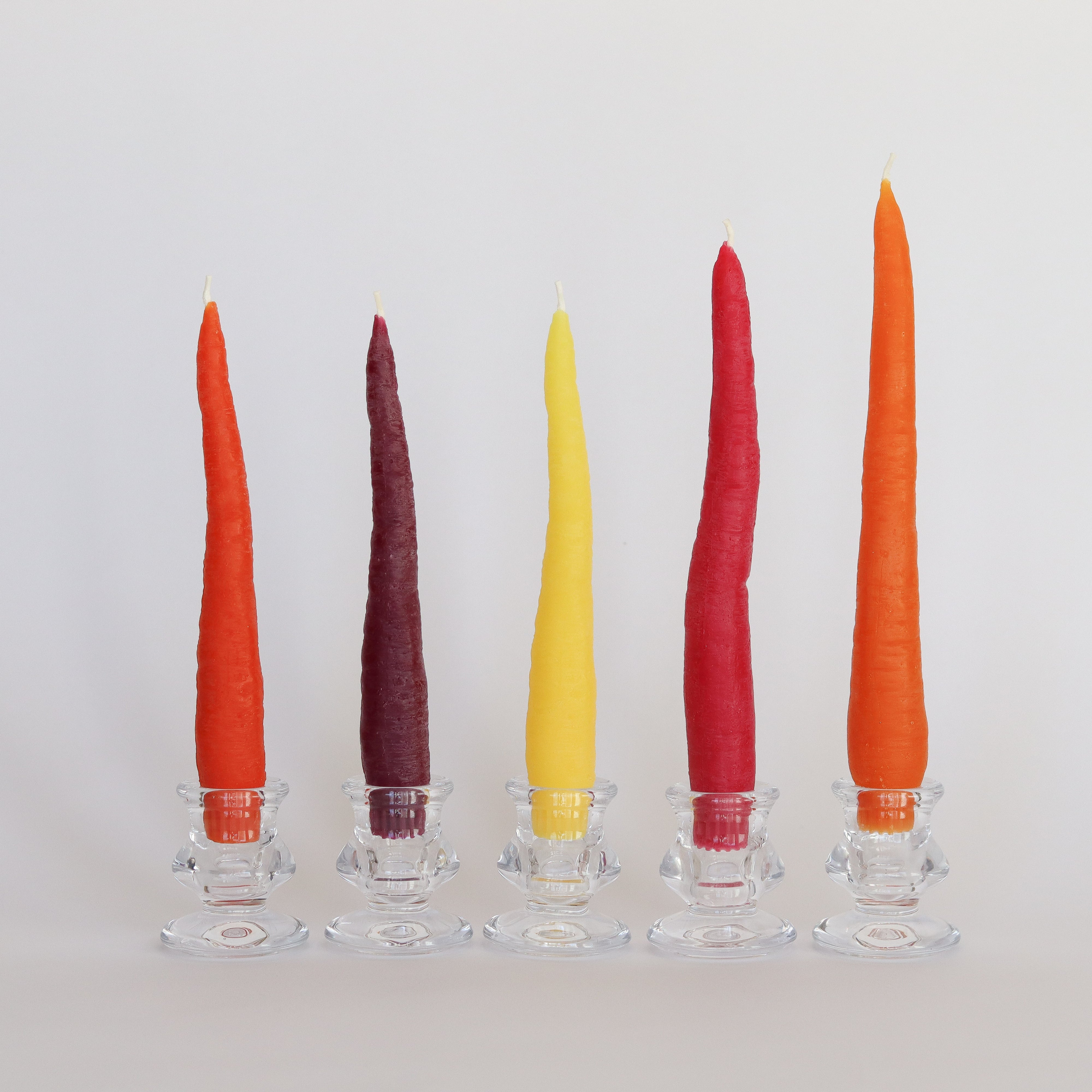 Five colorful candles in glass holders on a white background