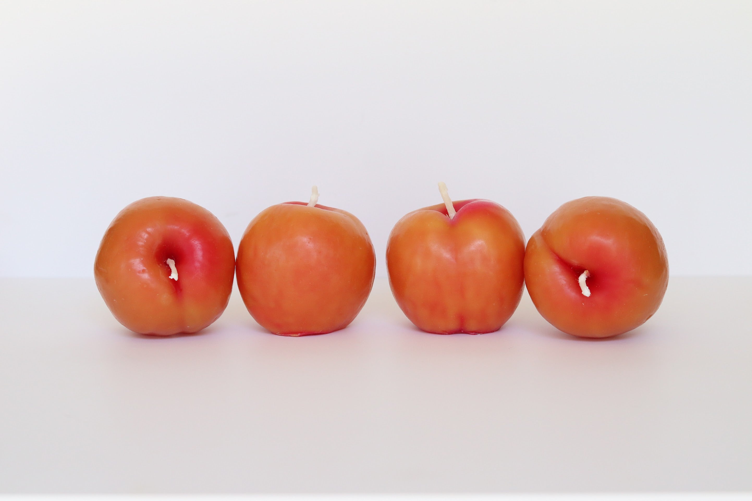 Four red apples lined up on a white background