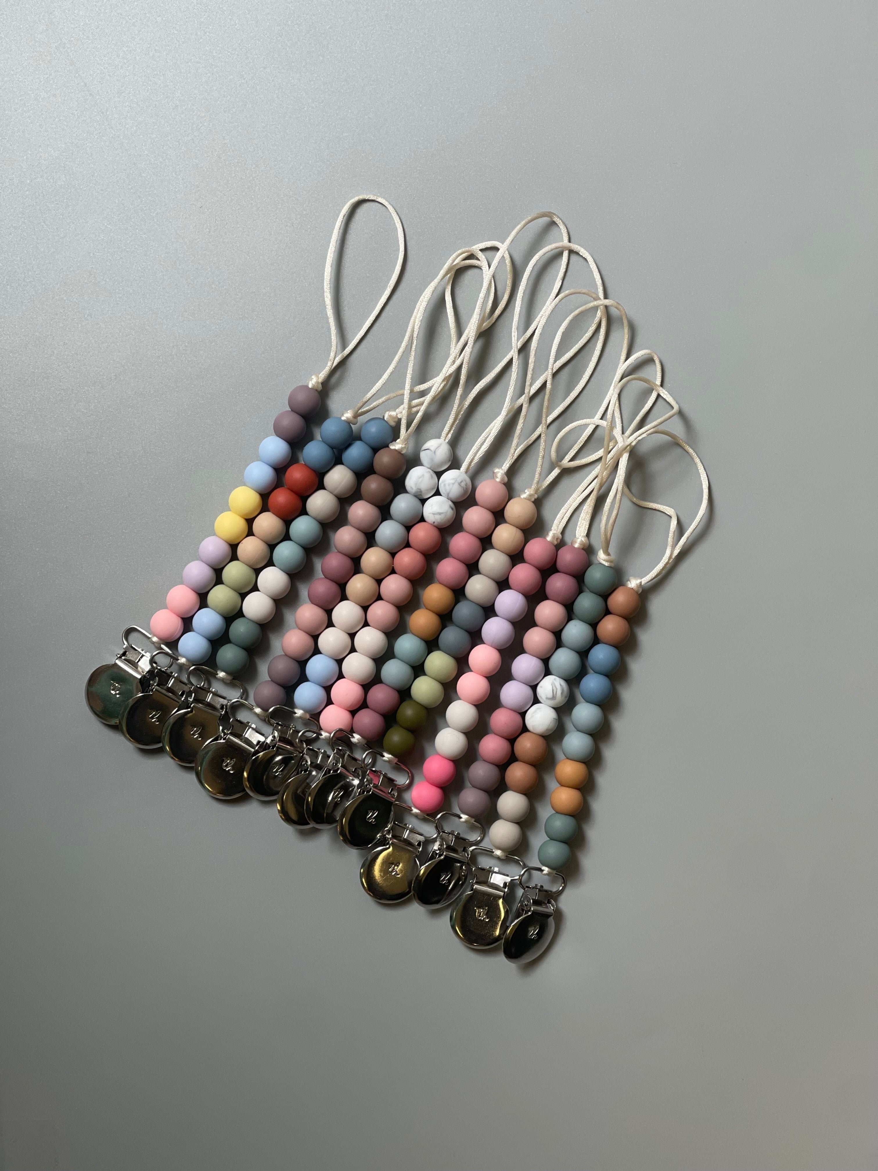 Set of colorful beaded lanyards with keychains on a gray background