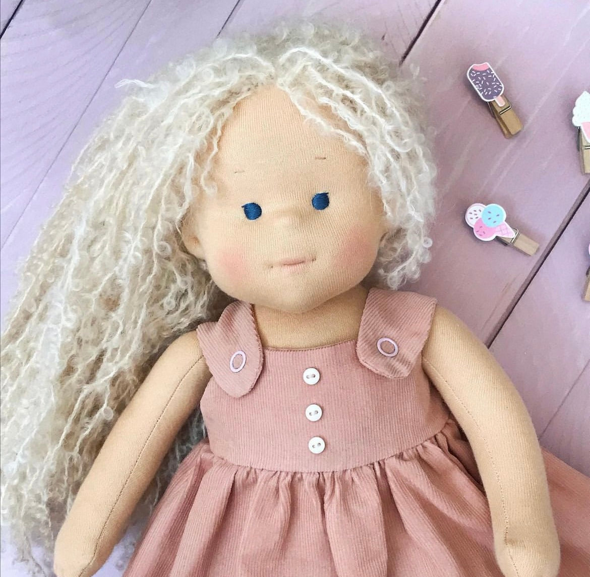 doll with blonde hair and a pink dress on a wooden surface