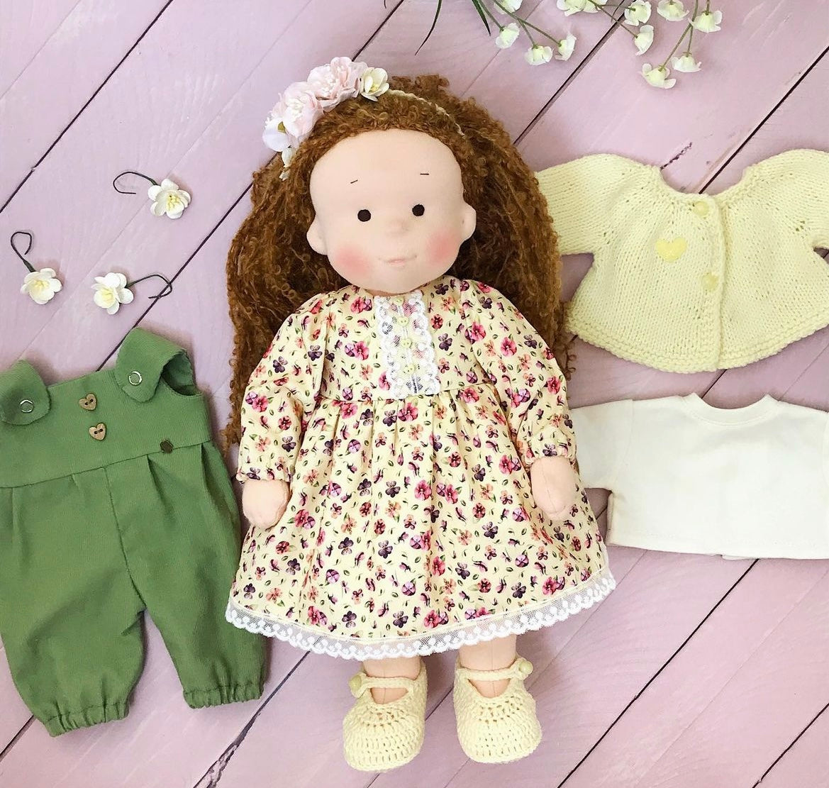 Doll with floral dress and green outfit on a wooden surface