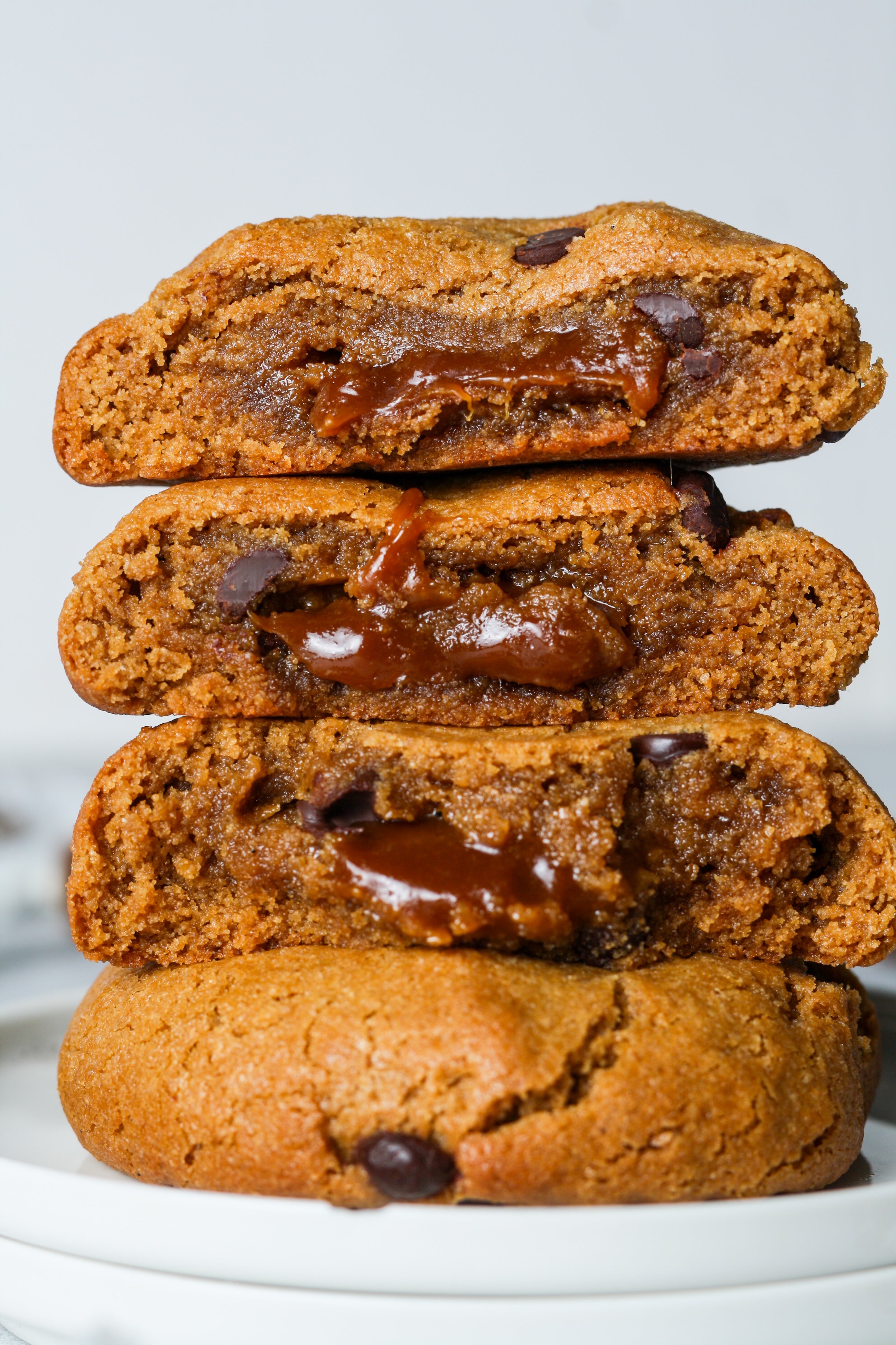 Stack of chocolate chip cookies with a gooey chocolate filling on a white plate.