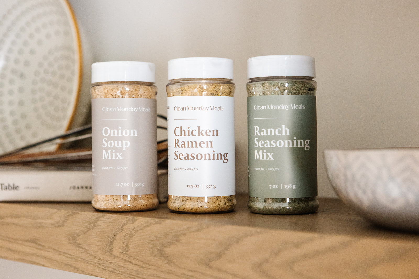 Three seasoning mix jars labeled 'Onion Soup Mix', 'Chicken Ramen Seasoning', and 'Ranch Seasoning Mix' on a wooden surface.