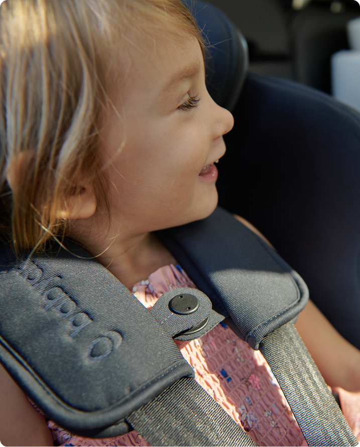 Child in a car seat with a close-up of the harness strap.
