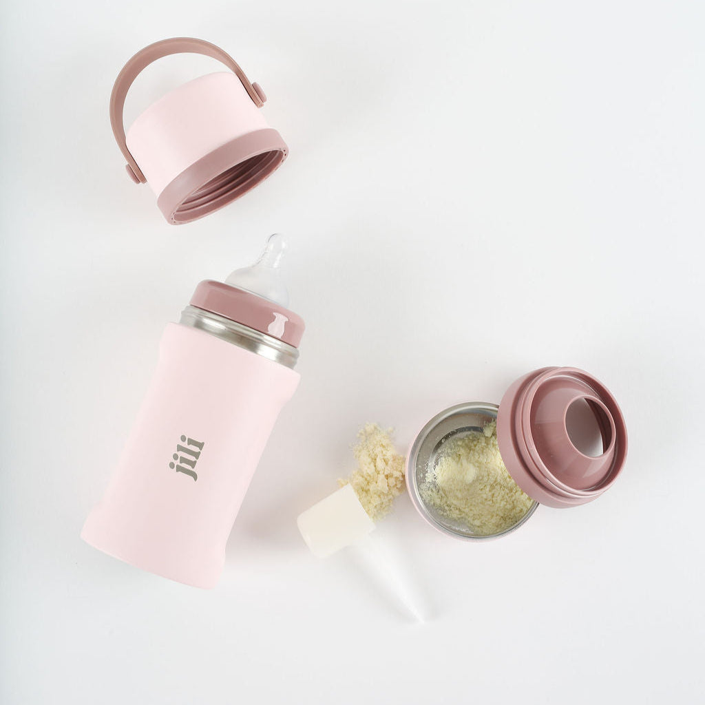 Pink baby bottle with accessories on a white background