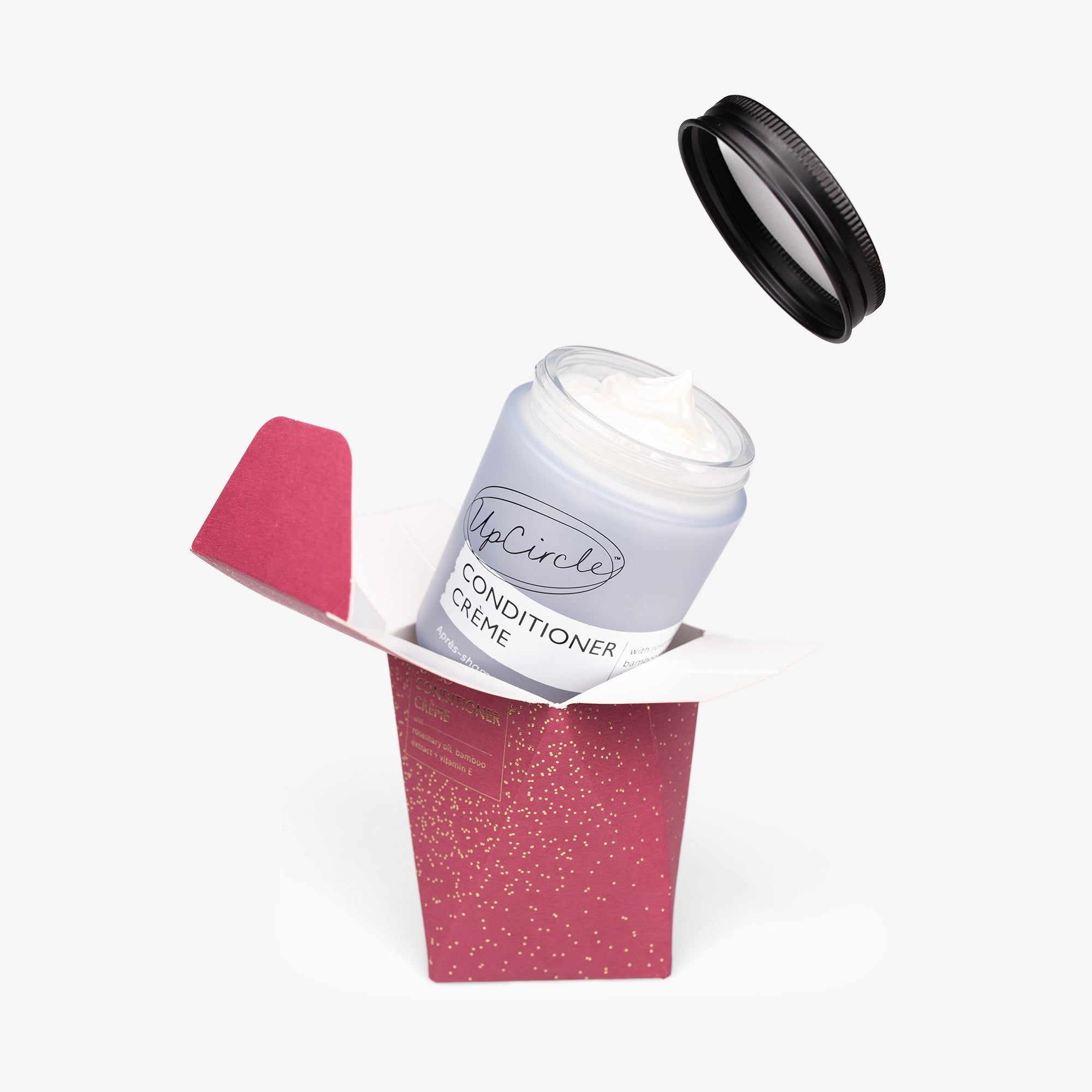 Conditioner cream in a red container with a black lid on a white background