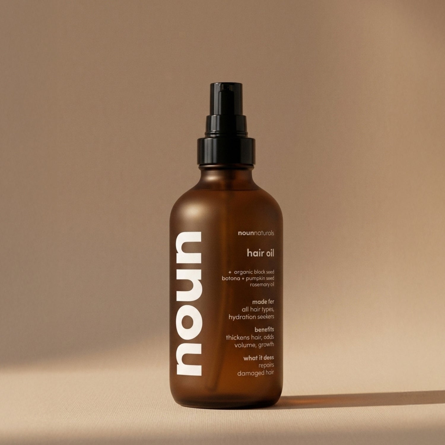 Brown bottle of noum hair oil on a beige background