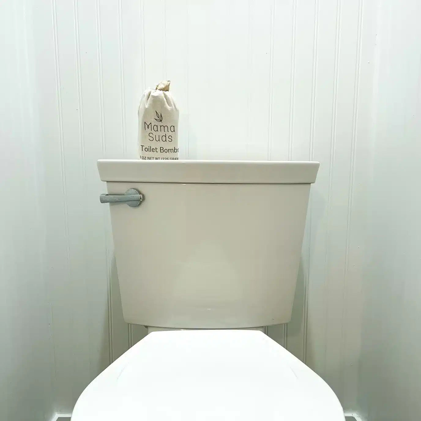 Mama Suds Non-Toxic Toilet Cleaning Tablets sitting on the back of a toilet.