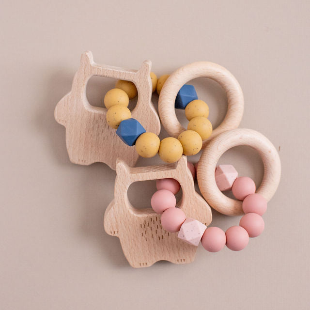 Set of wooden teething rings with colorful beads on a beige background